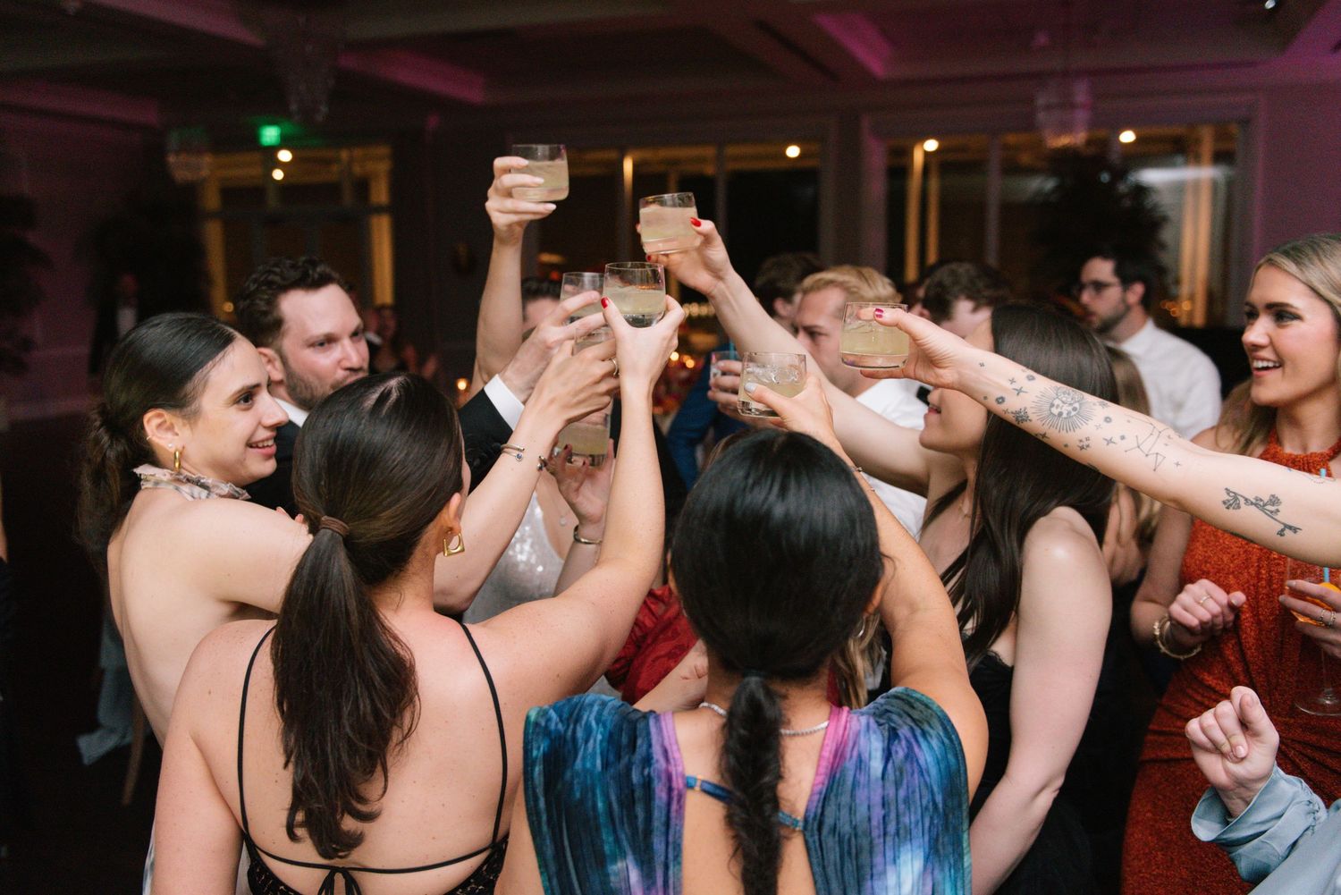 Wedding celebration with guests raising glasses in a festive toast during reception.