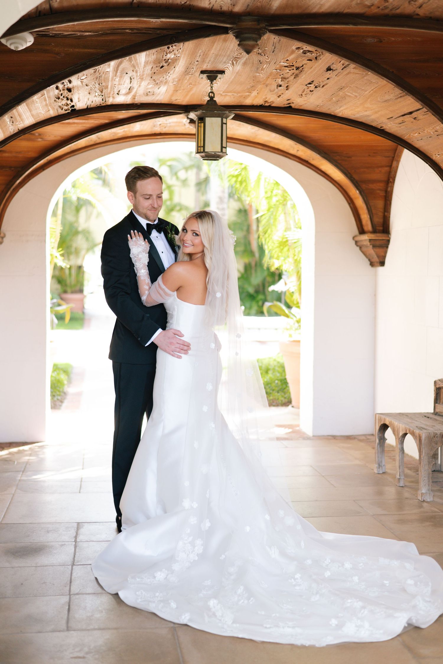 Romantic wedding photo sequence under arched walkway with elegant architectural details.