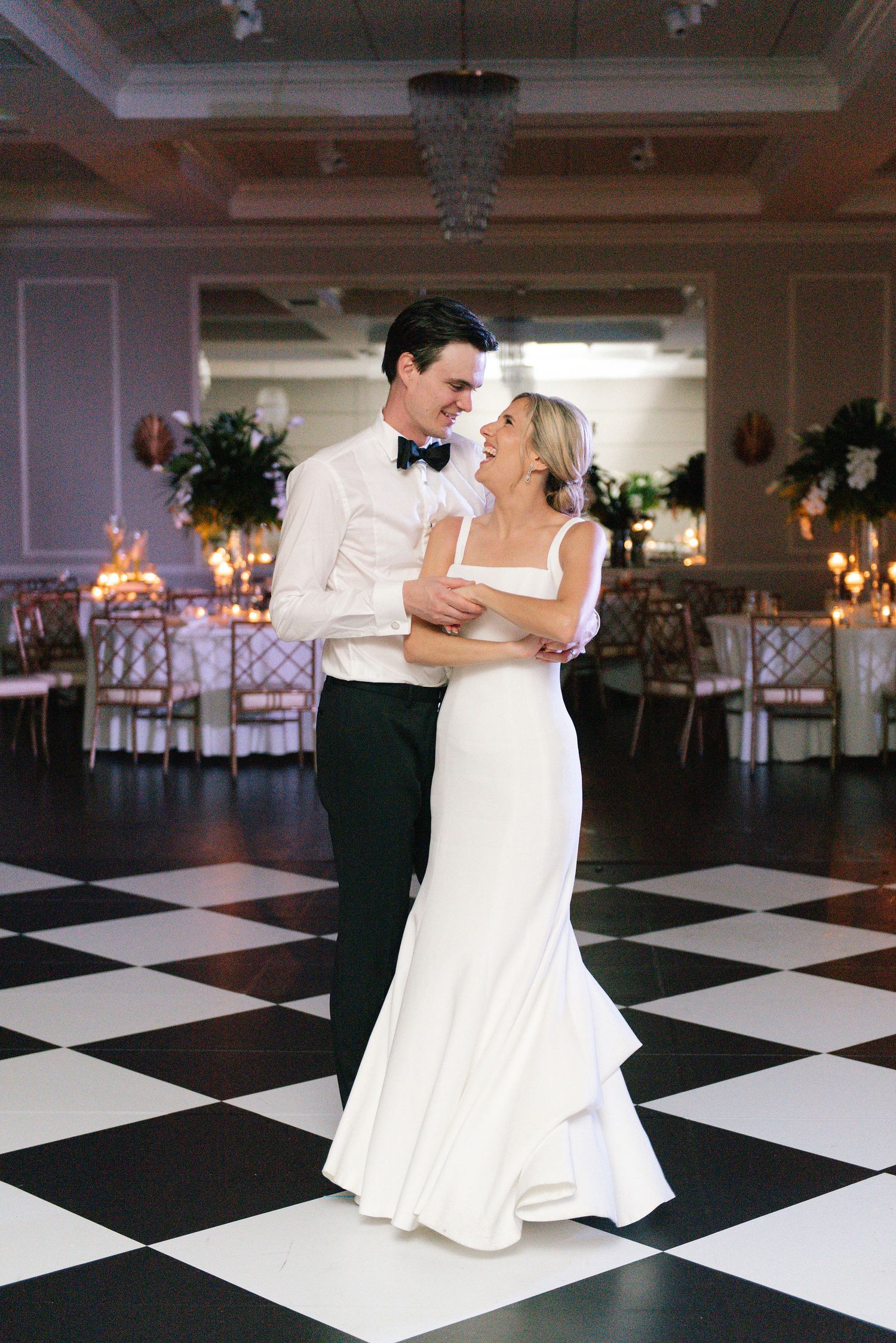 Couple sharing an intimate dance on a black and white checkered ballroom floor.
