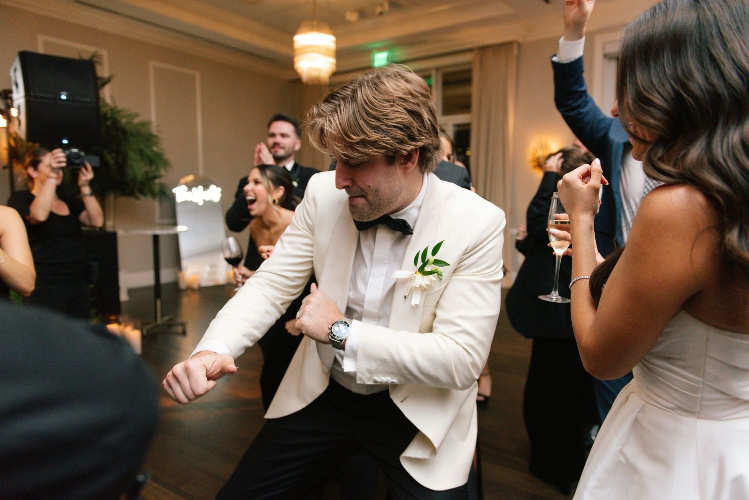 Wedding celebration with energetic dancing at an indoor reception venue.