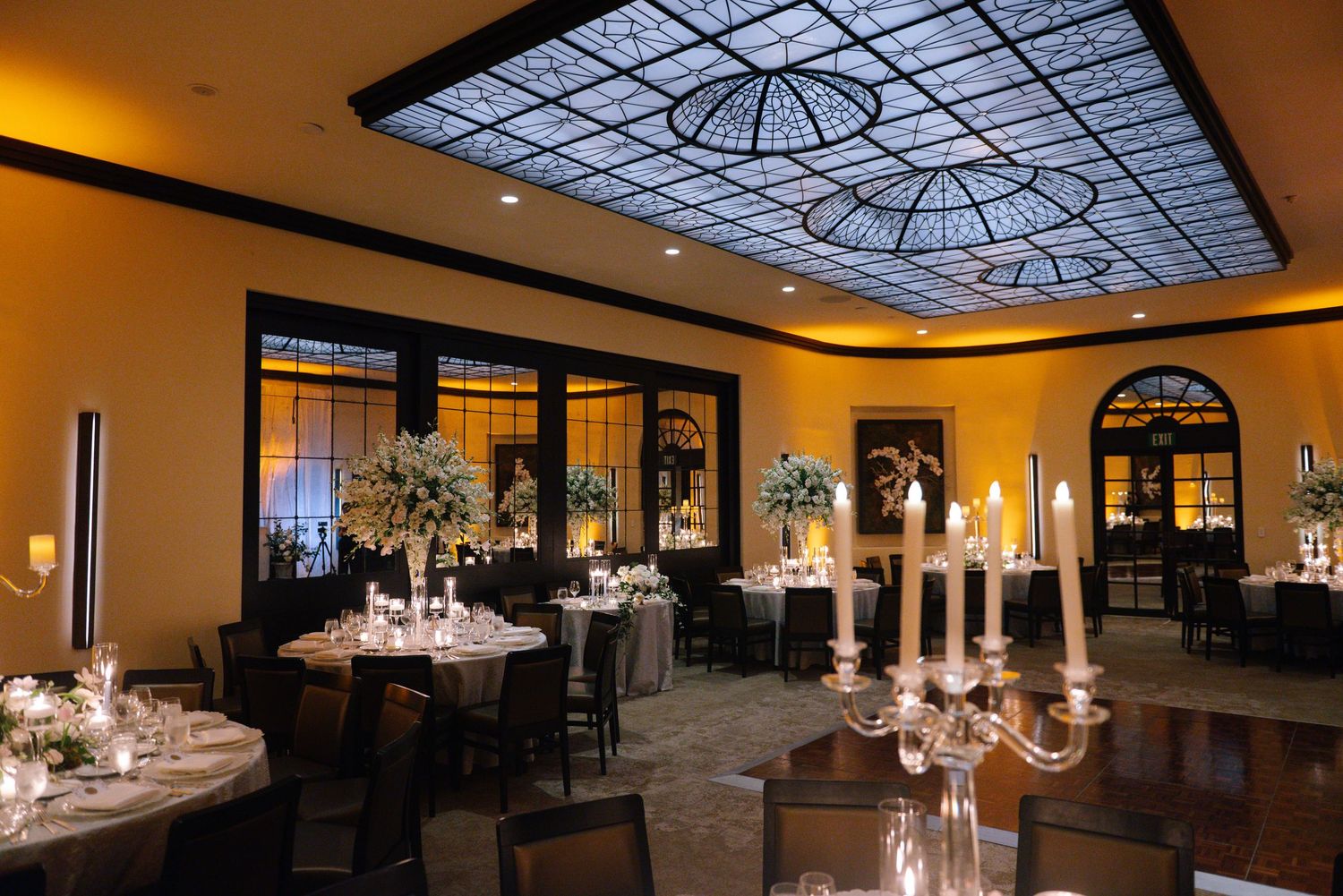 Elegant ballroom venue with ornate ceiling, crystal chandeliers and formal table settings for an upscale event.