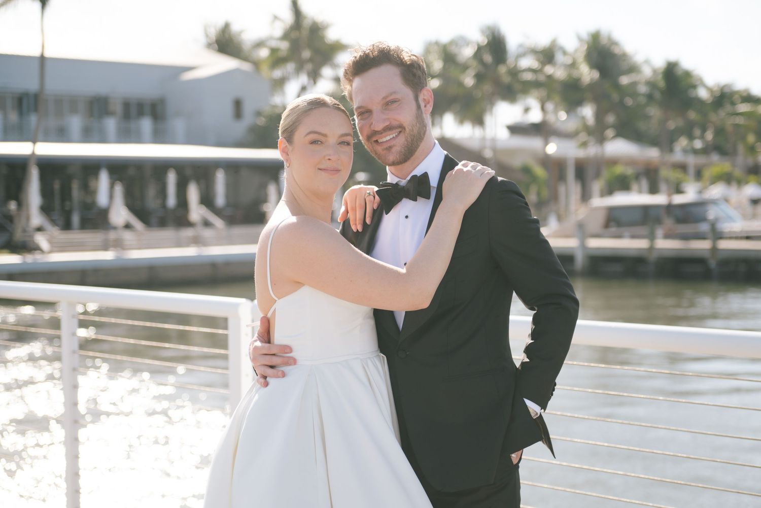 Wedding party poses for romantic waterfront photos at sunset in Florida.