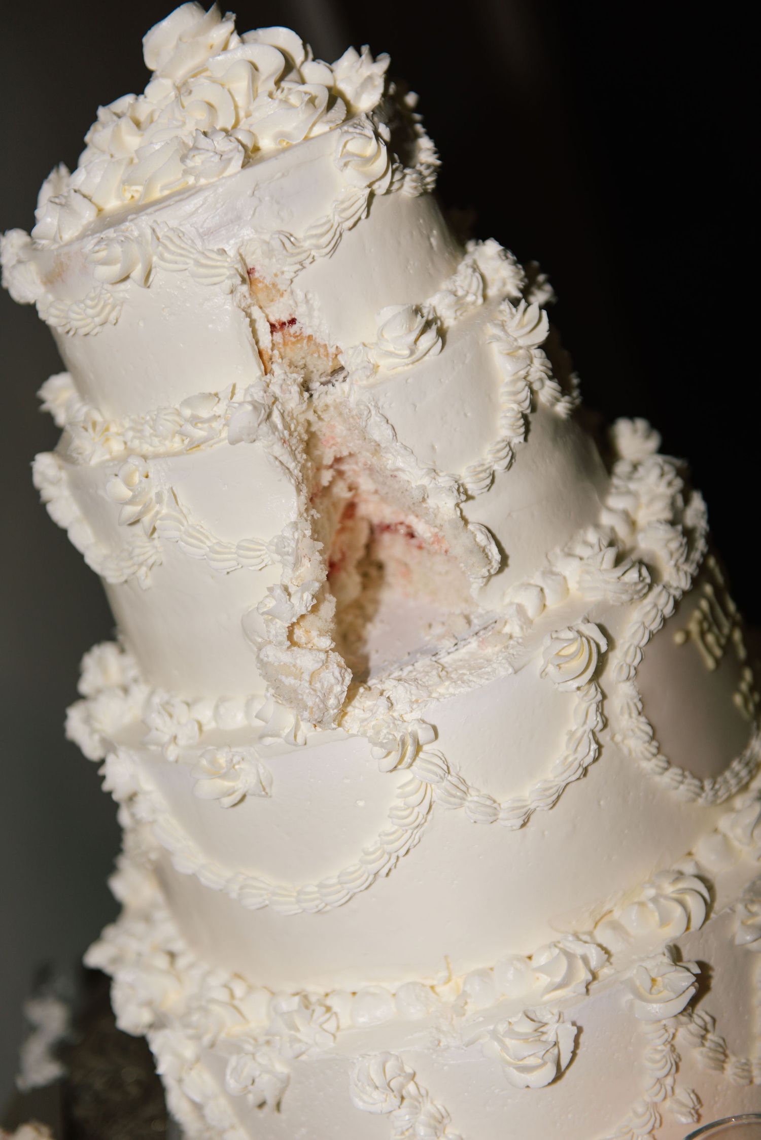 Close-up of an ornate white wedding cake with intricate piped frosting details and delicate floral decorations.