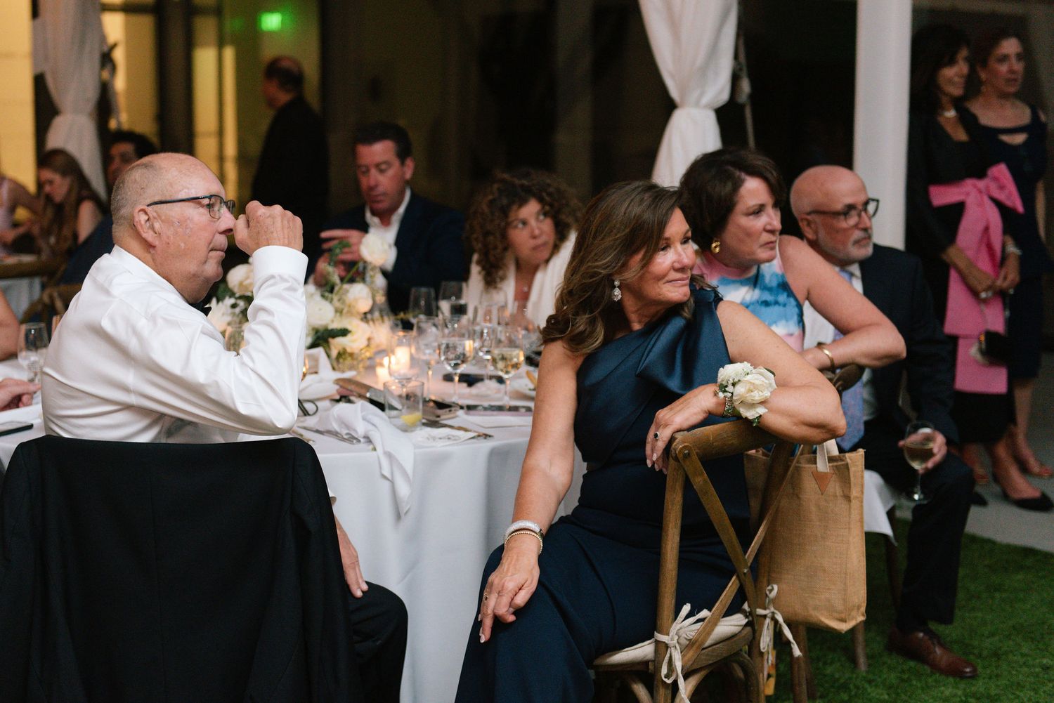 Wedding guests celebrate with raised glasses during an indoor reception with wooden beams.