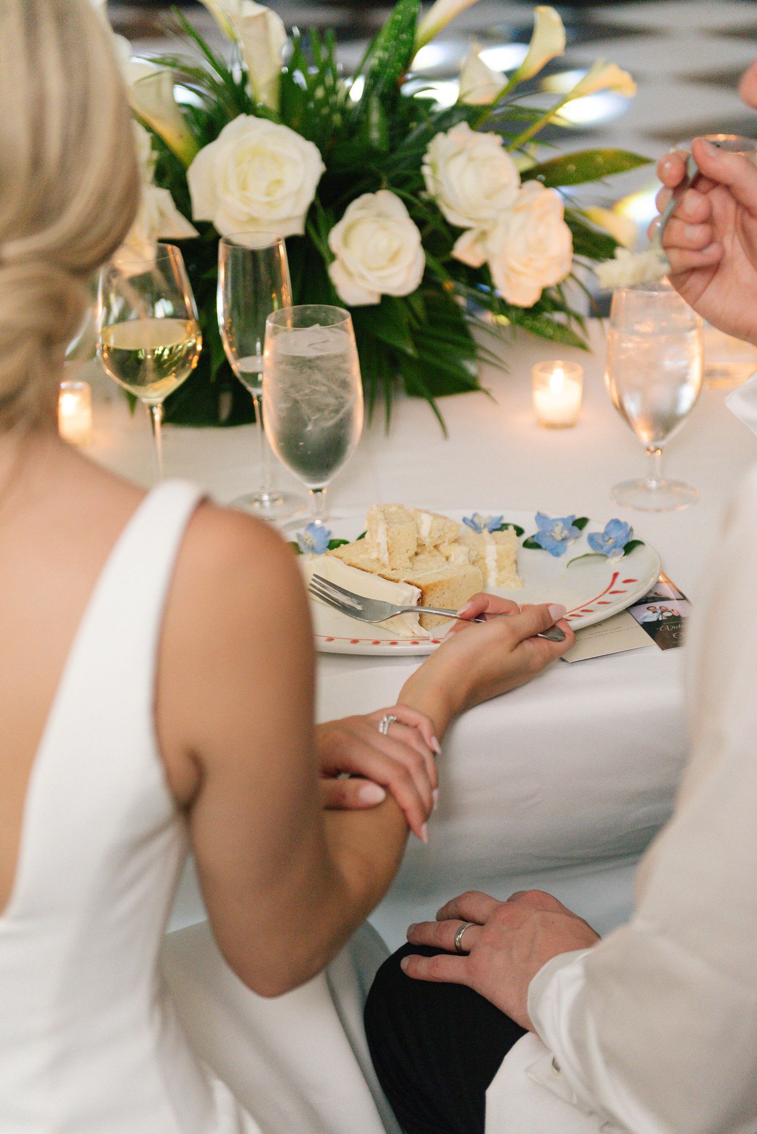Wedding table setting with white roses, candles and elegant place settings.