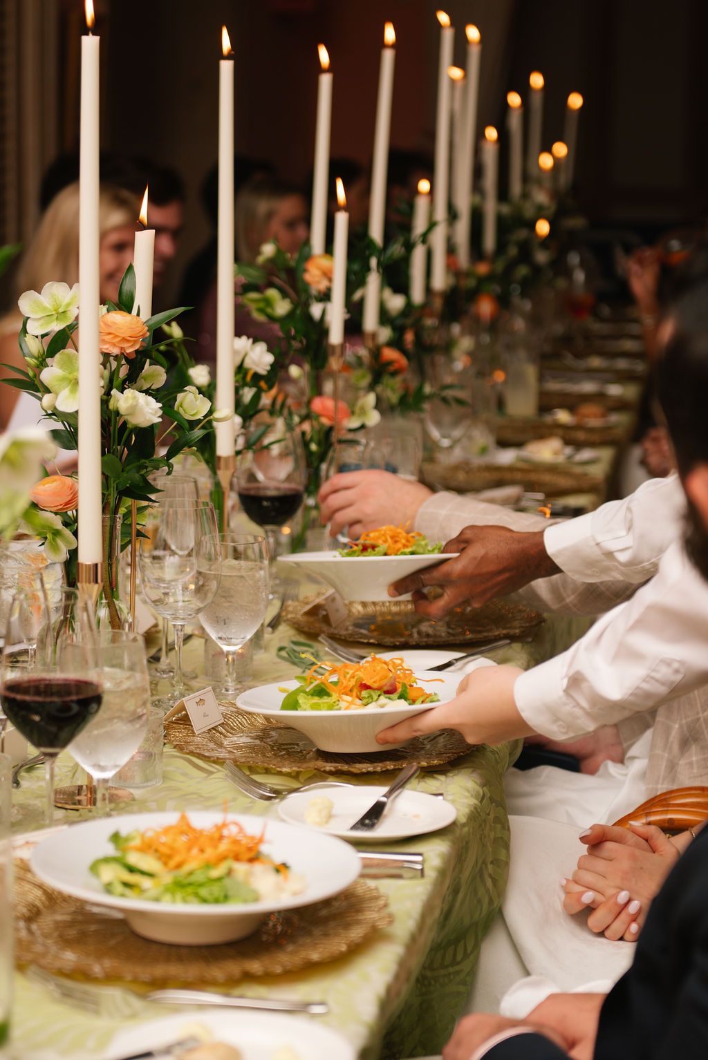 Elegant table setting with lit candles, flowers, and plated dinner service.