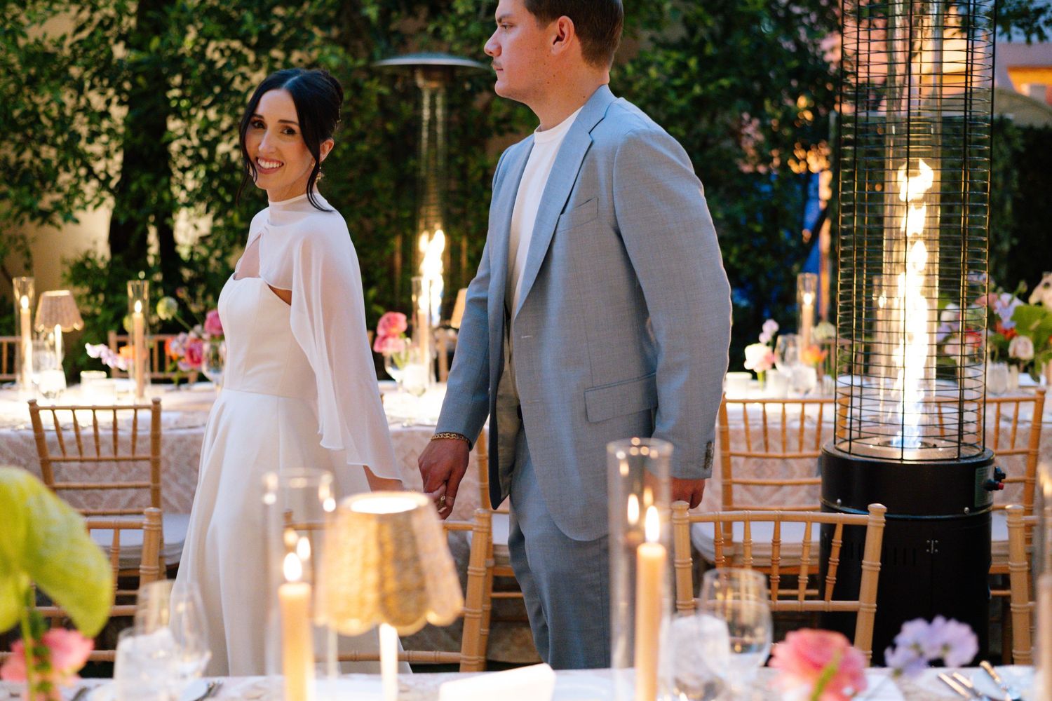 Outdoor wedding venue with string lights and elegant decor at sunset.