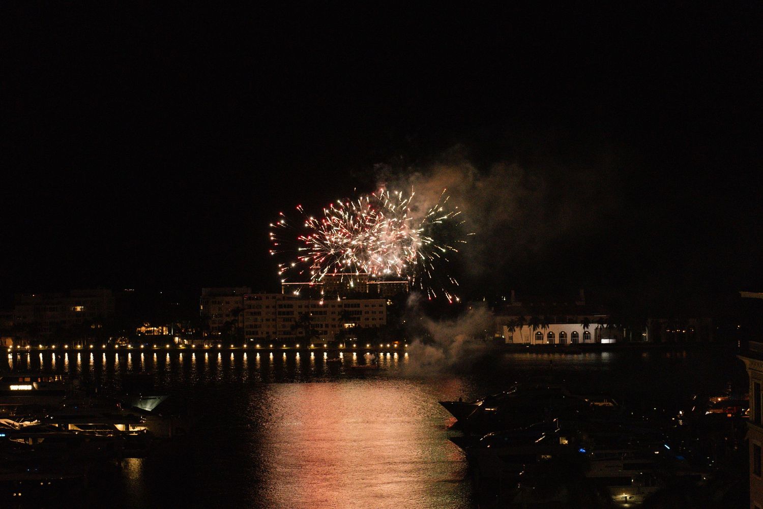 Panoramic view of fireworks display over a waterfront at night.