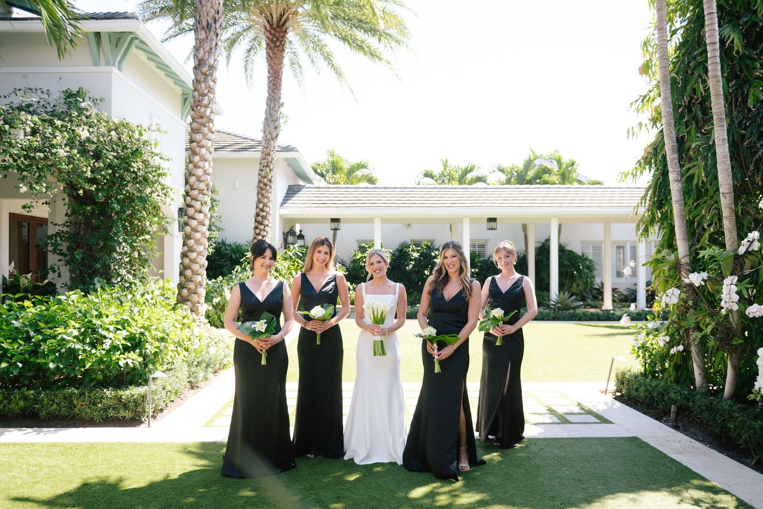 Wedding party walking along tropical garden path with palm trees.