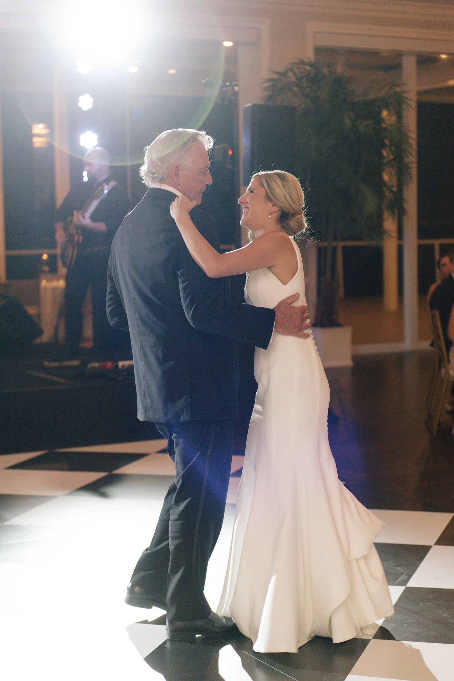 Wedding dance captured in motion on a black and white checkered floor.