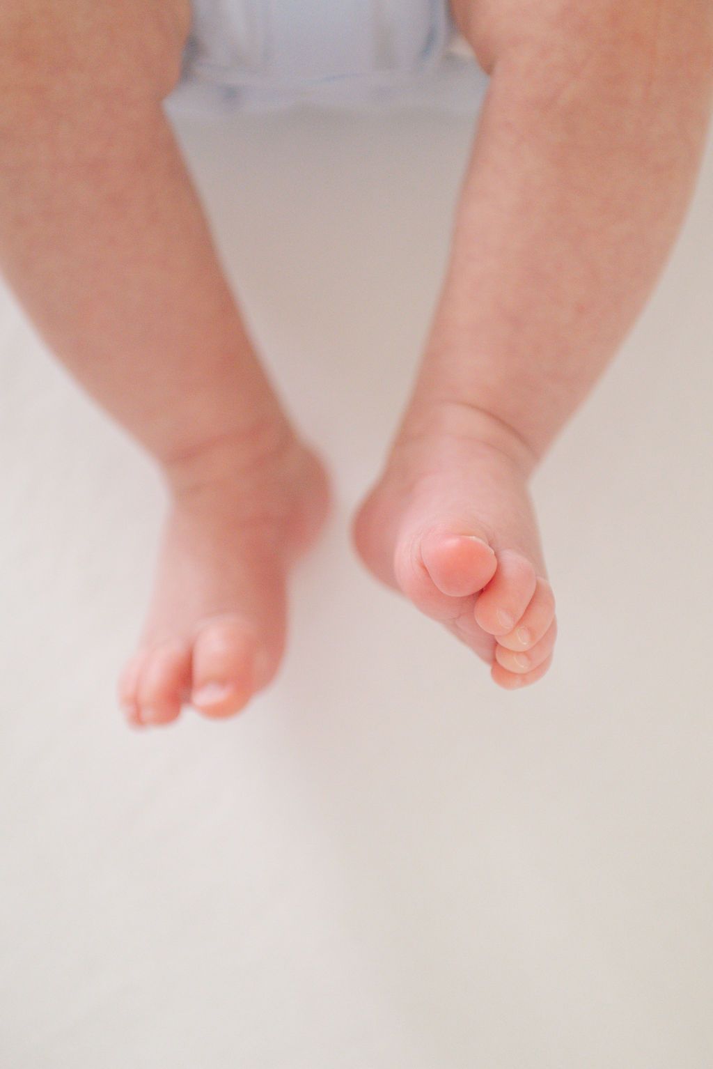 Close-up of tiny newborn baby feet against a soft white background.