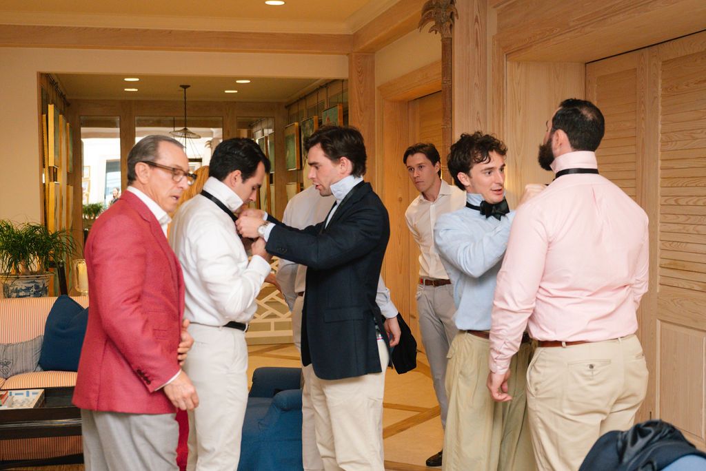 Group getting ready in formal attire before an event in a wood-paneled hallway.