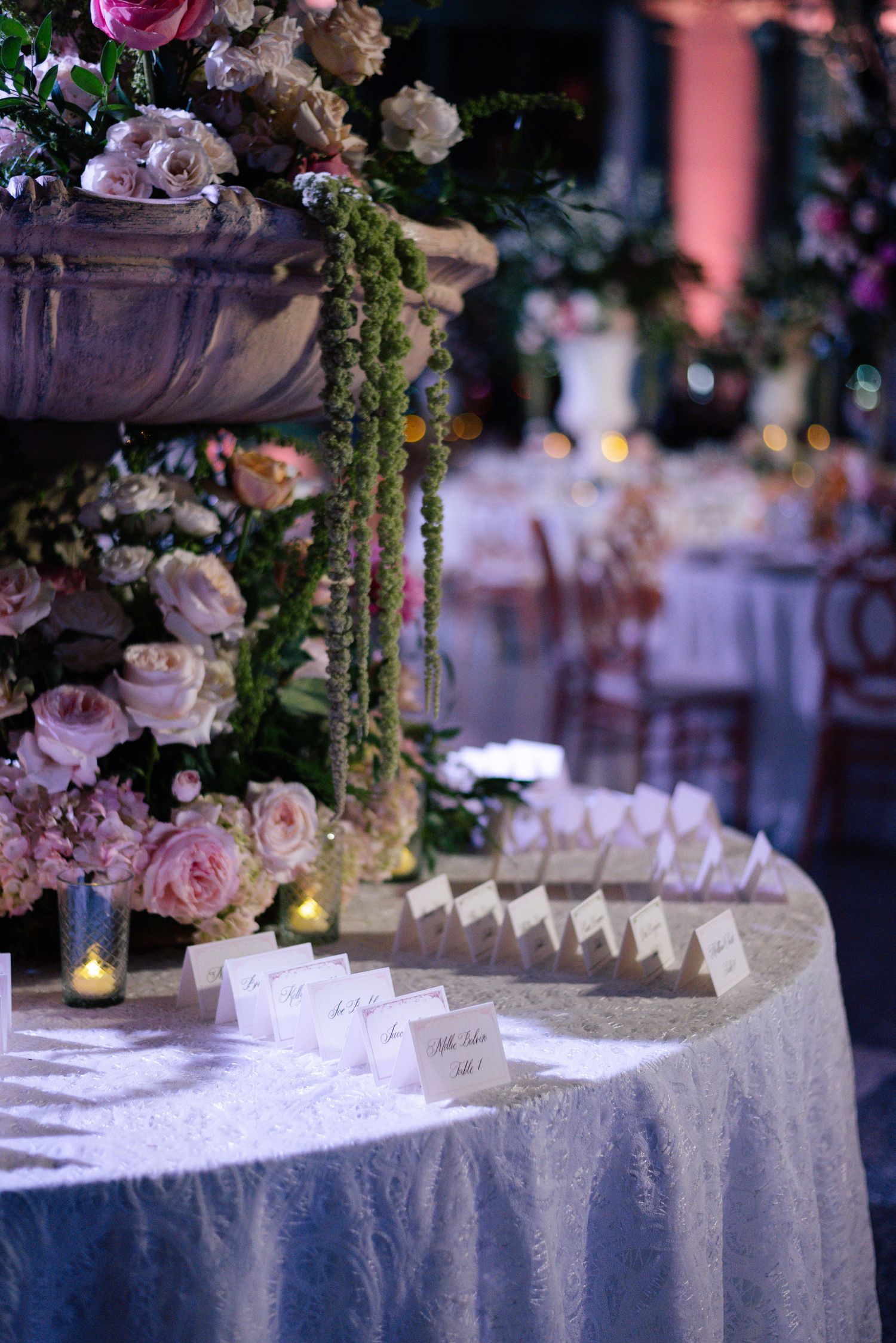 Luxurious wedding reception table with place cards and floral arrangements under soft lighting.