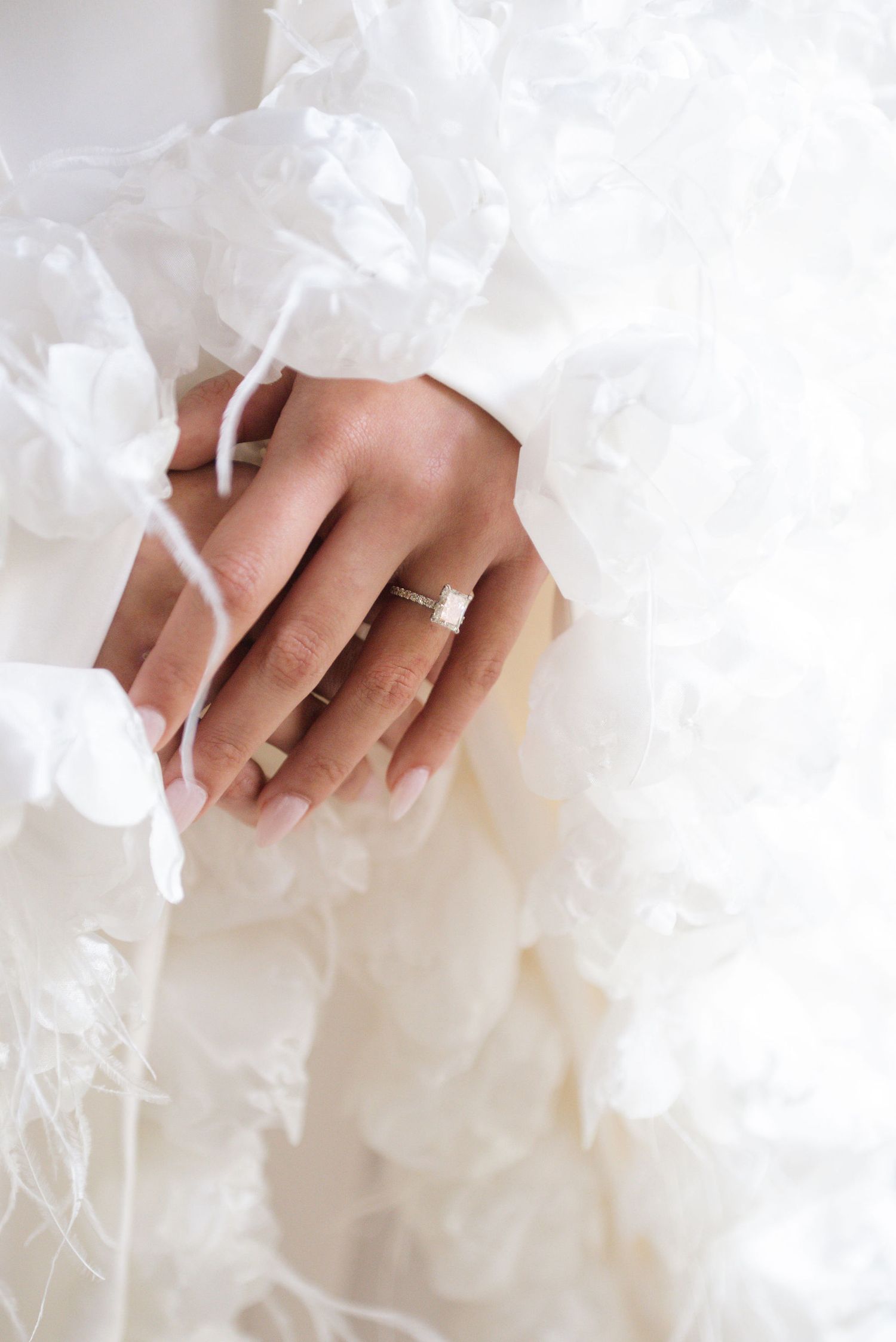 Close-up detail of hands resting on white fabric with delicate lace details.