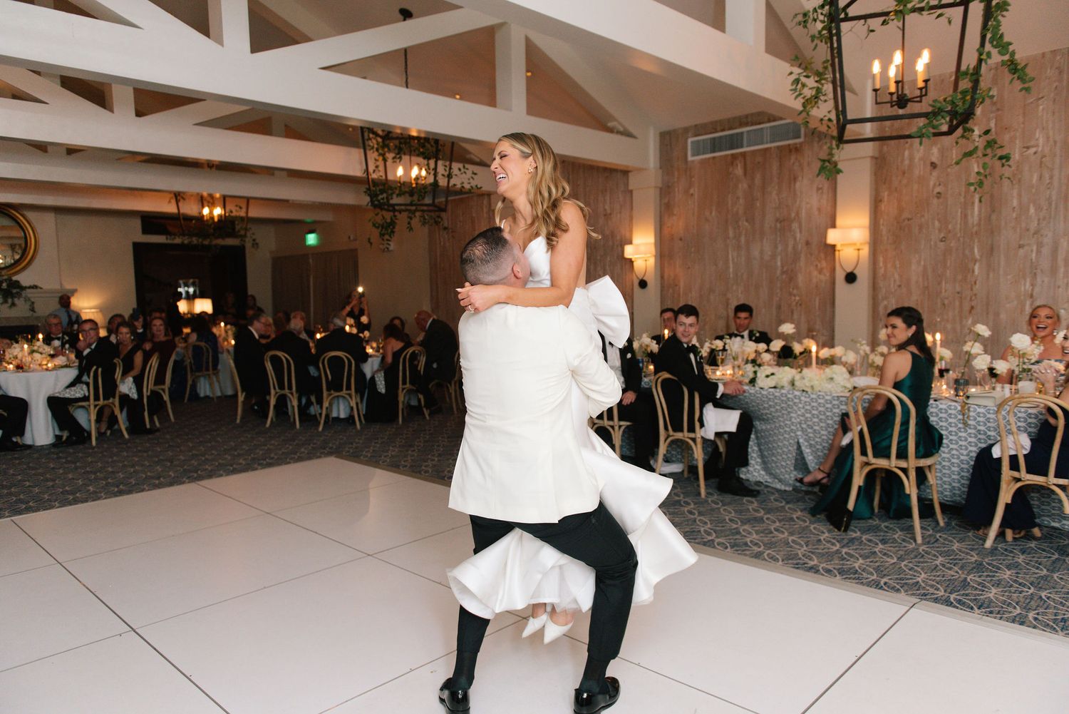 Wedding guests dance together on a white dance floor during an elegant reception celebration.