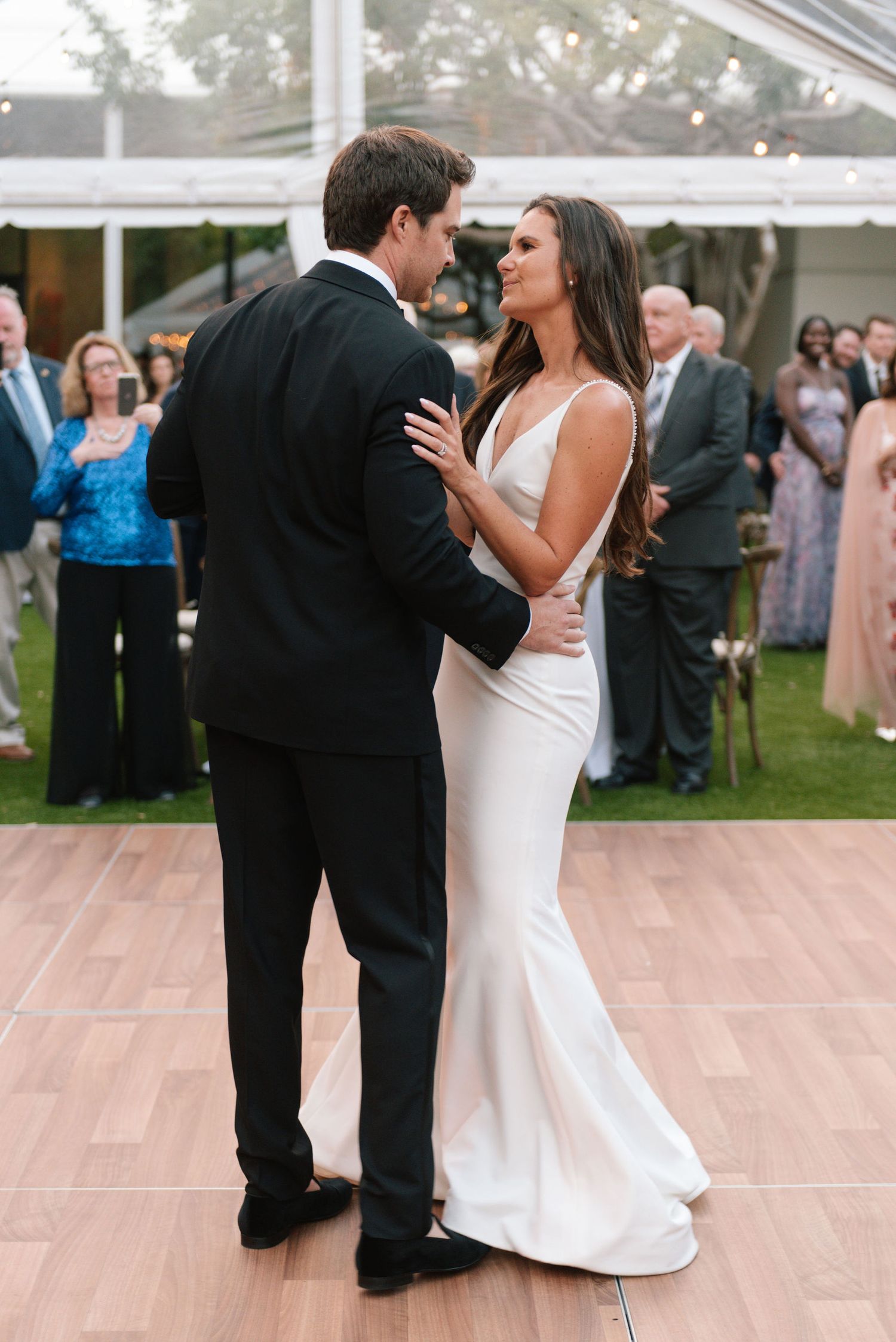 Couples dancing together on a wooden dance floor at an outdoor evening wedding reception.