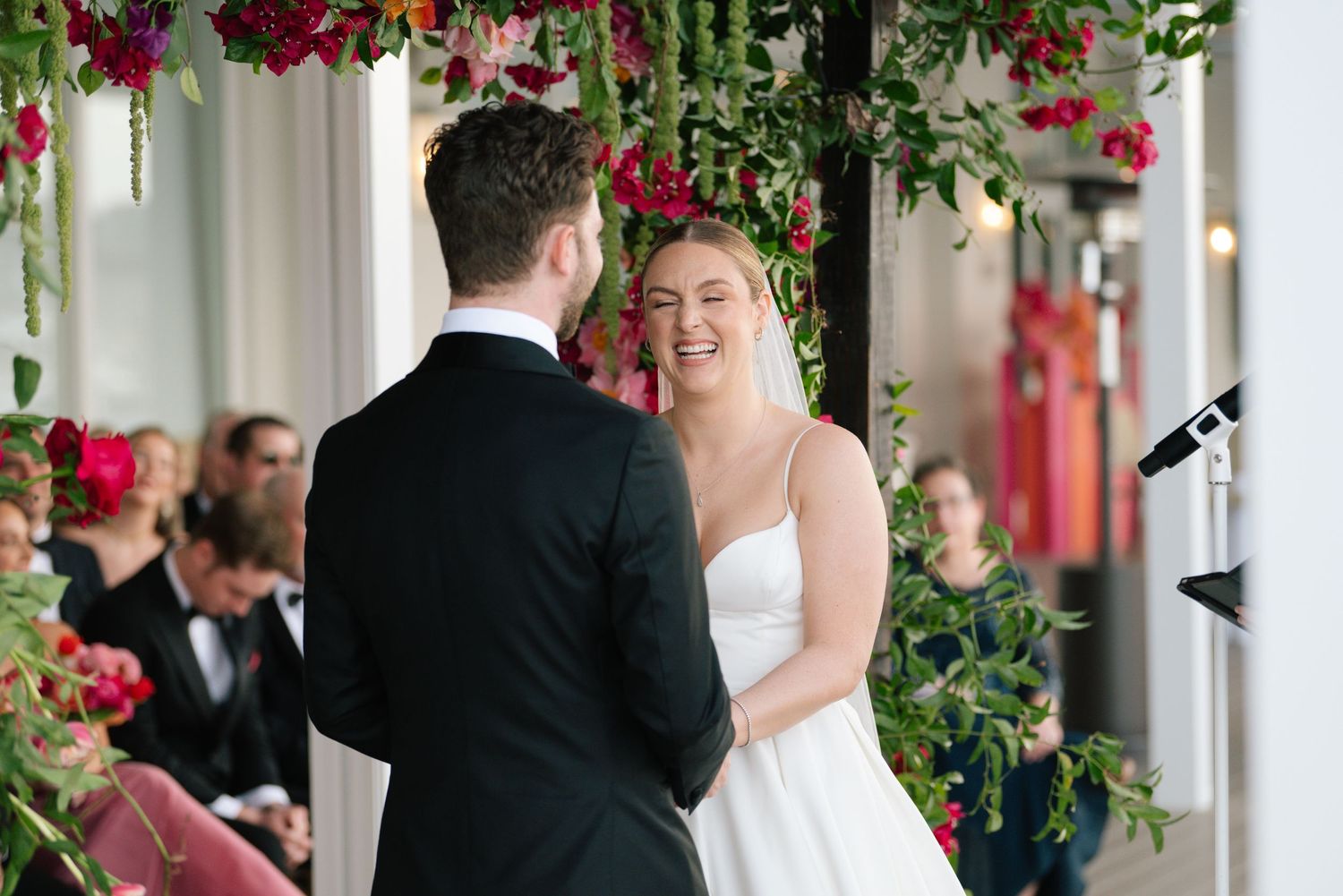 Wedding ceremony under floral arch with red bougainvillea flowers.