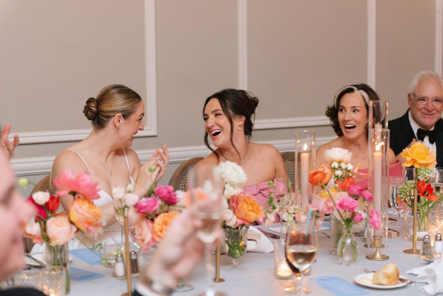 Reception table settings decorated with soft pink and peach floral centerpieces.