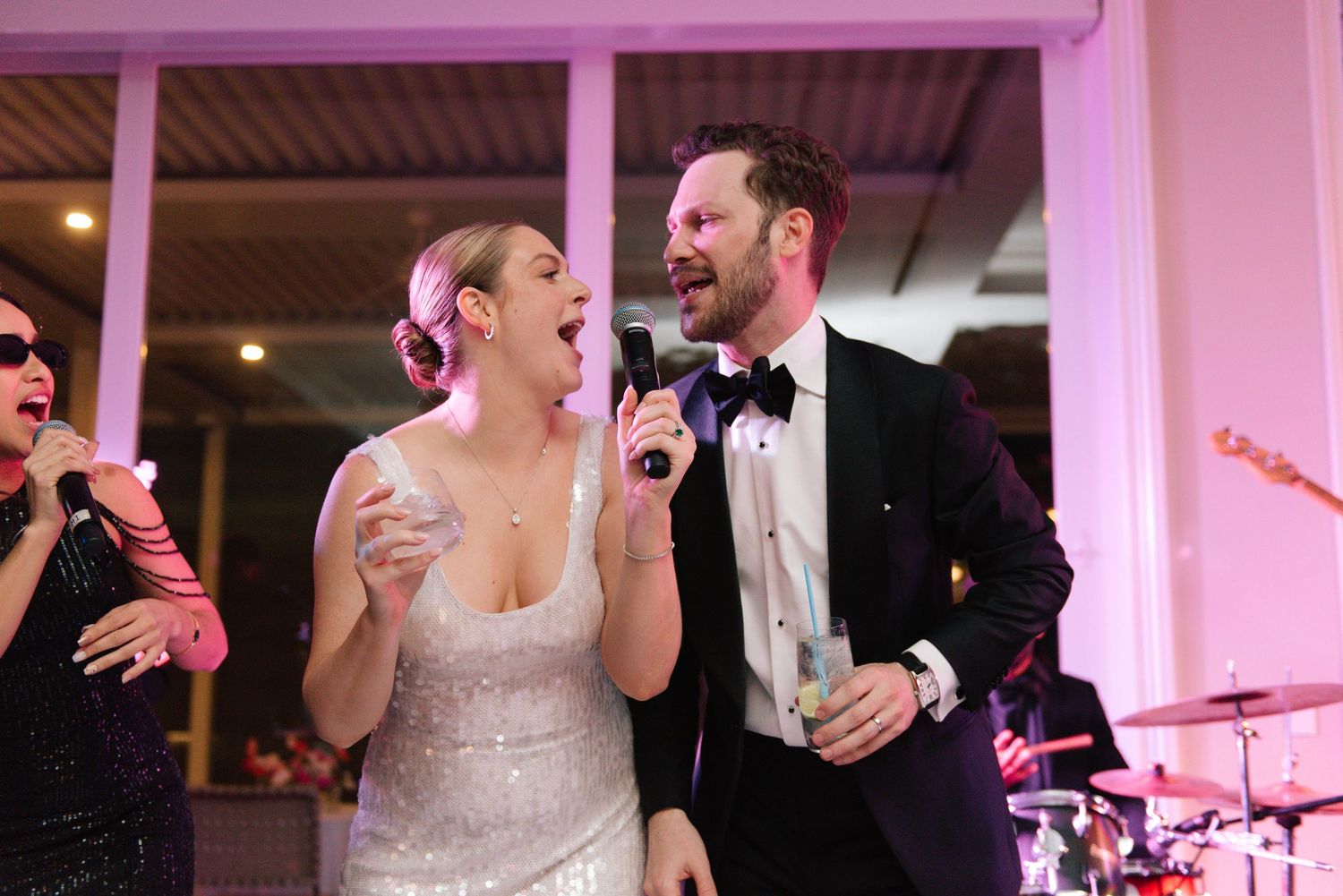 Wedding reception venue illuminated in purple lighting with elegant table settings.
