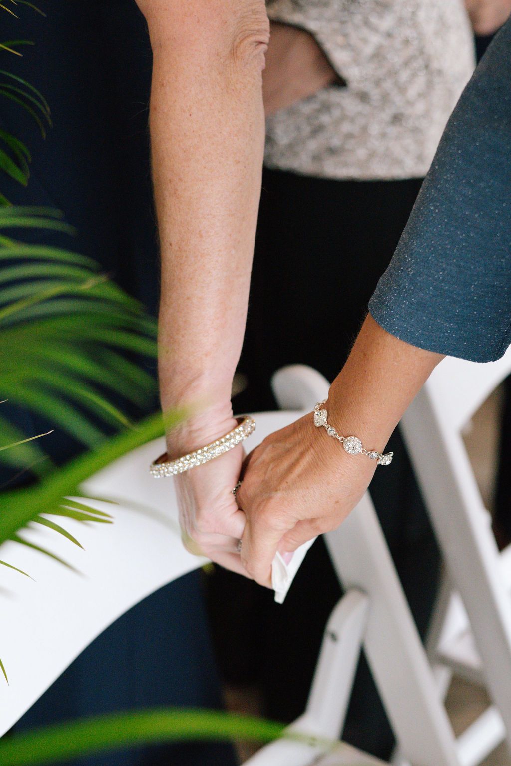 Close-up of hands wearing formal jewelry at a wedding ceremony.