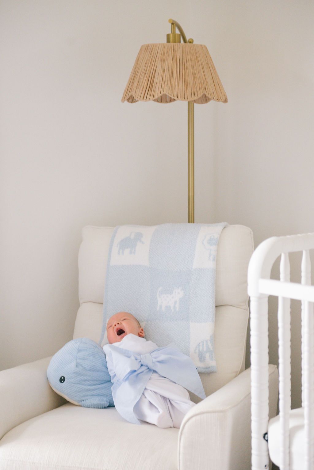 Nursery room decor with light blue pillows and gold lamp on white furniture.