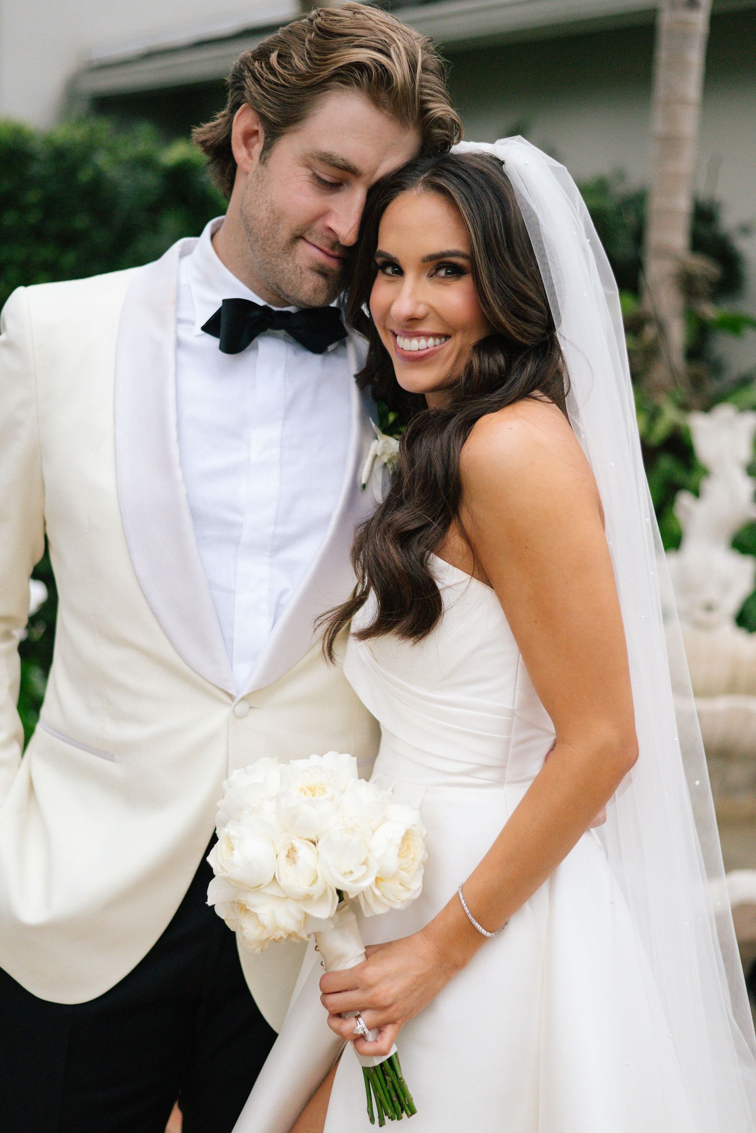 A romantic wedding moment captured in soft lighting with white roses and elegant attire.