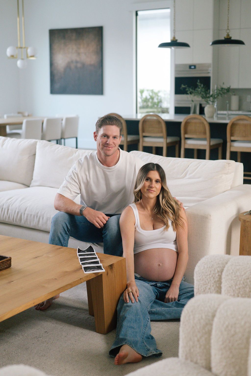 Couple sharing pregnancy news while looking at sonogram pictures in their living room.