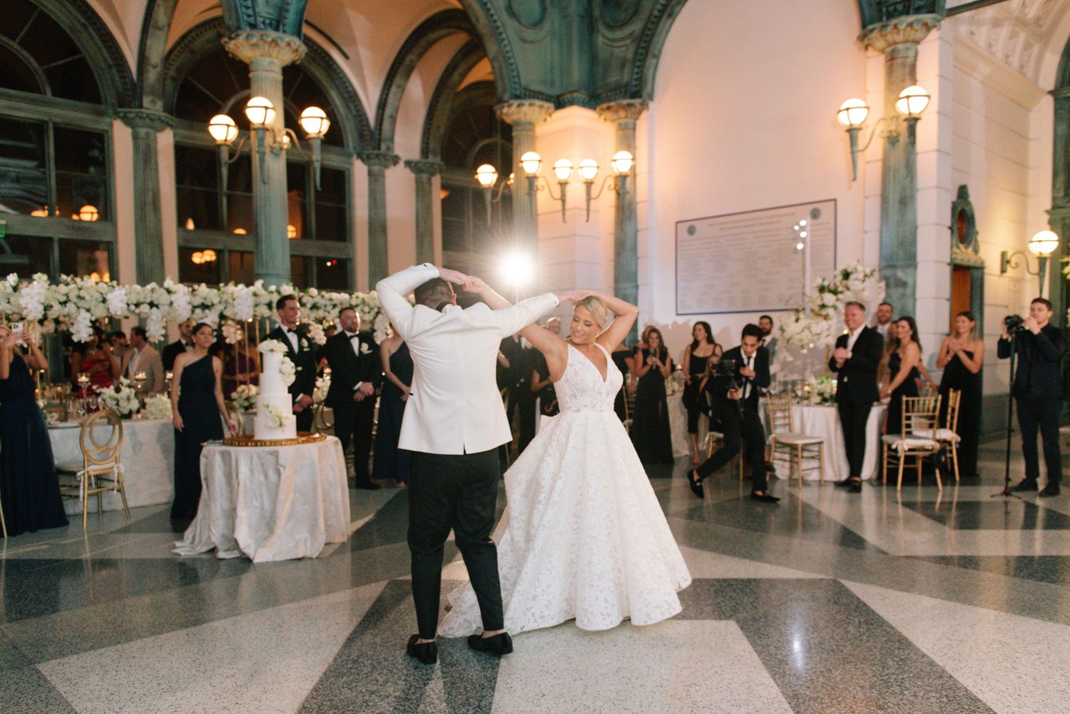 Bride and groom sharing first dance at grand ballroom wedding reception.