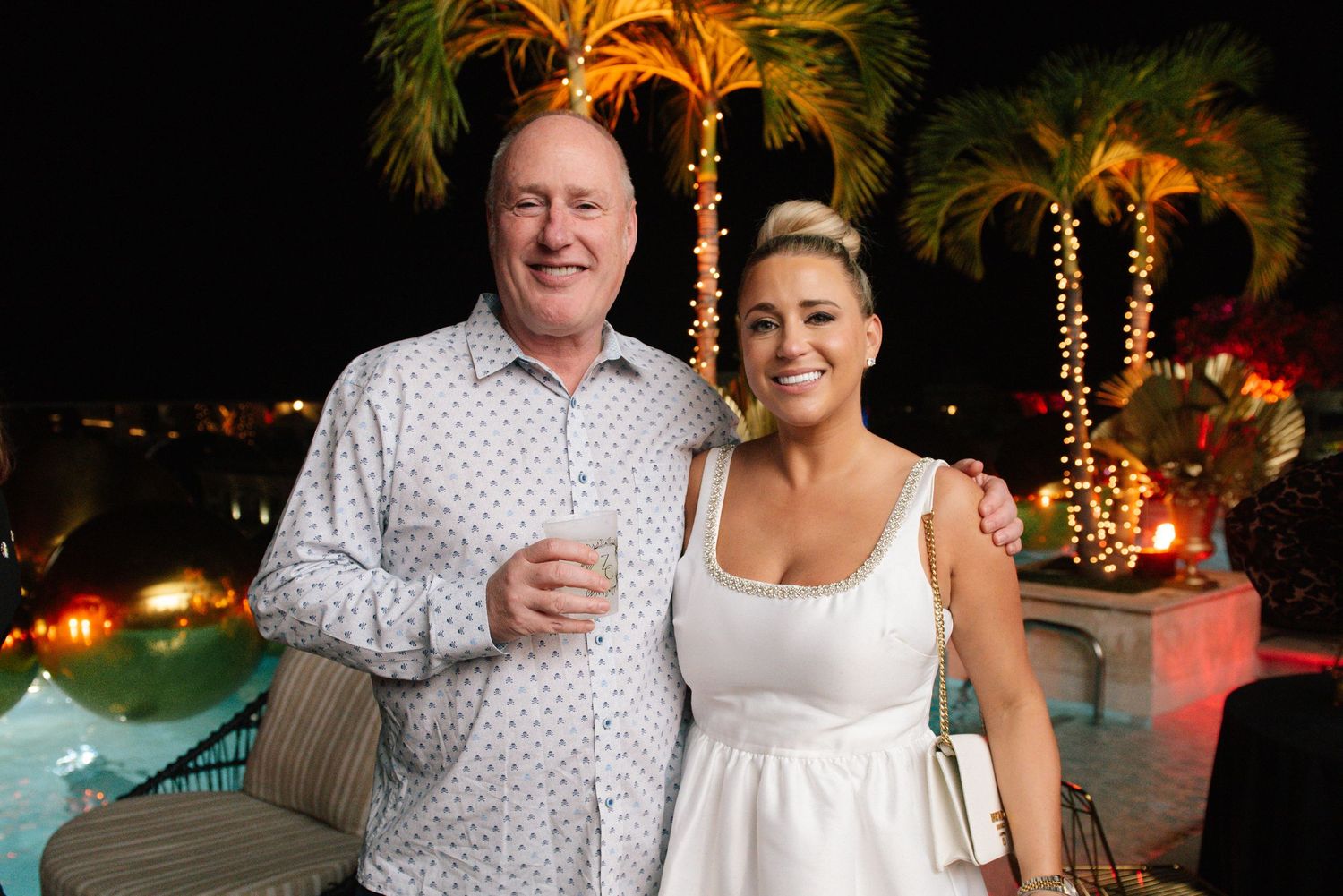 Outdoor evening celebration with palm trees and string lights creating a tropical ambiance.