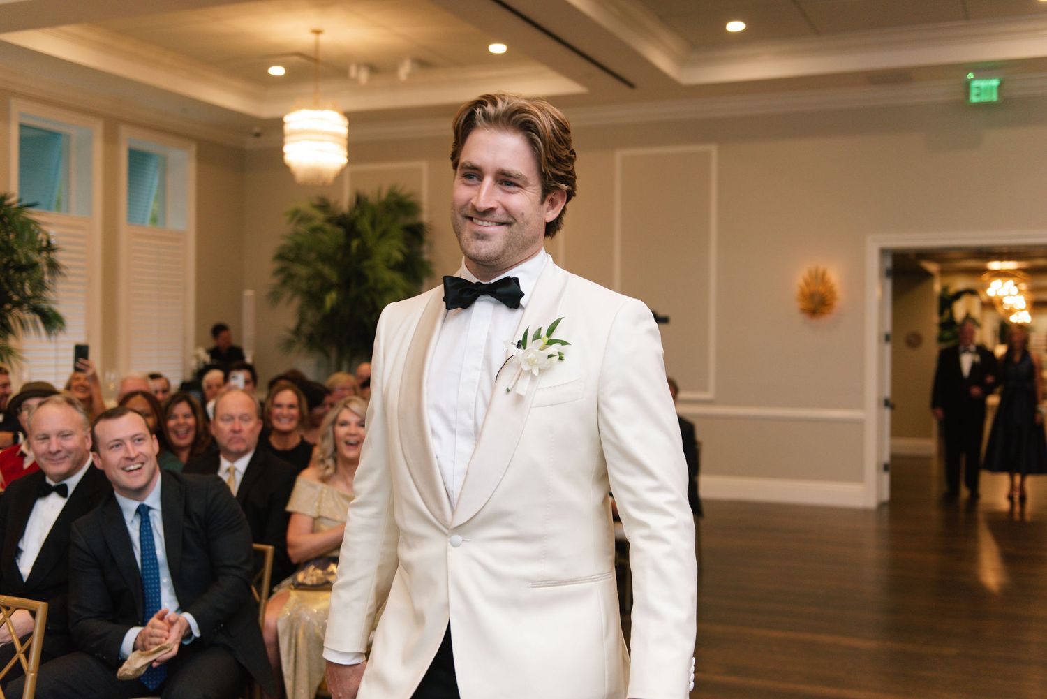 Wedding ceremony in an elegant ballroom with white and gold decor.