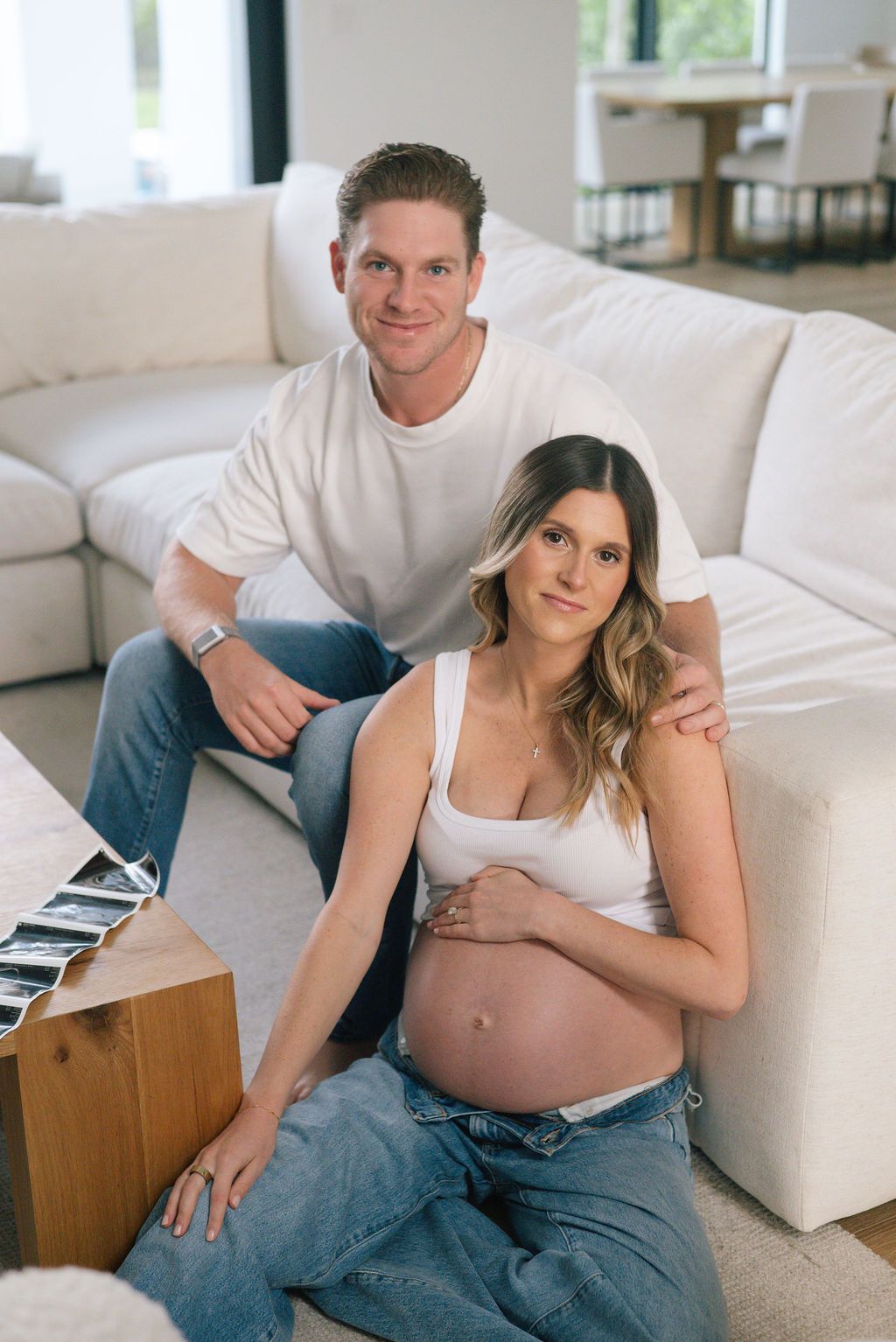 Expectant couple reviewing ultrasound photos together in modern living space.