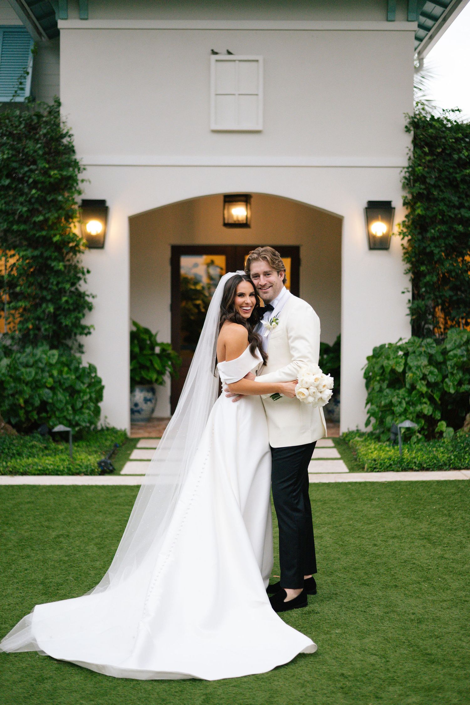 An elegant wedding photo session on a lush green lawn with classic architecture in the background.