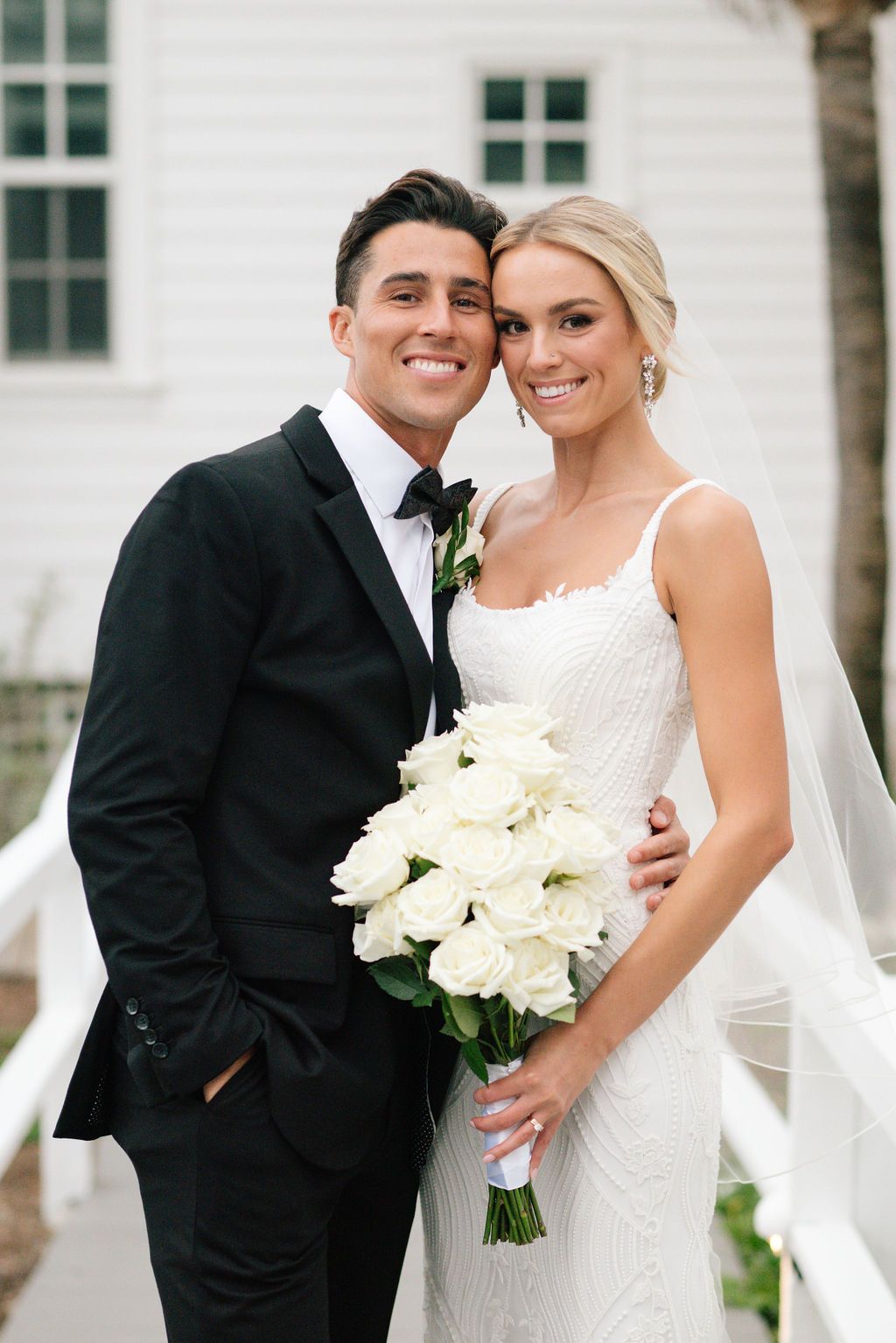 Elegant wedding portraits featuring white roses and coastal architecture.