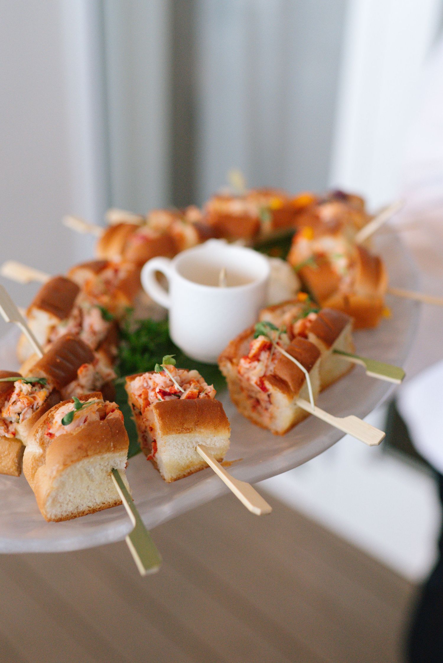 Appetizer skewers arranged on white serving plates at catered event.