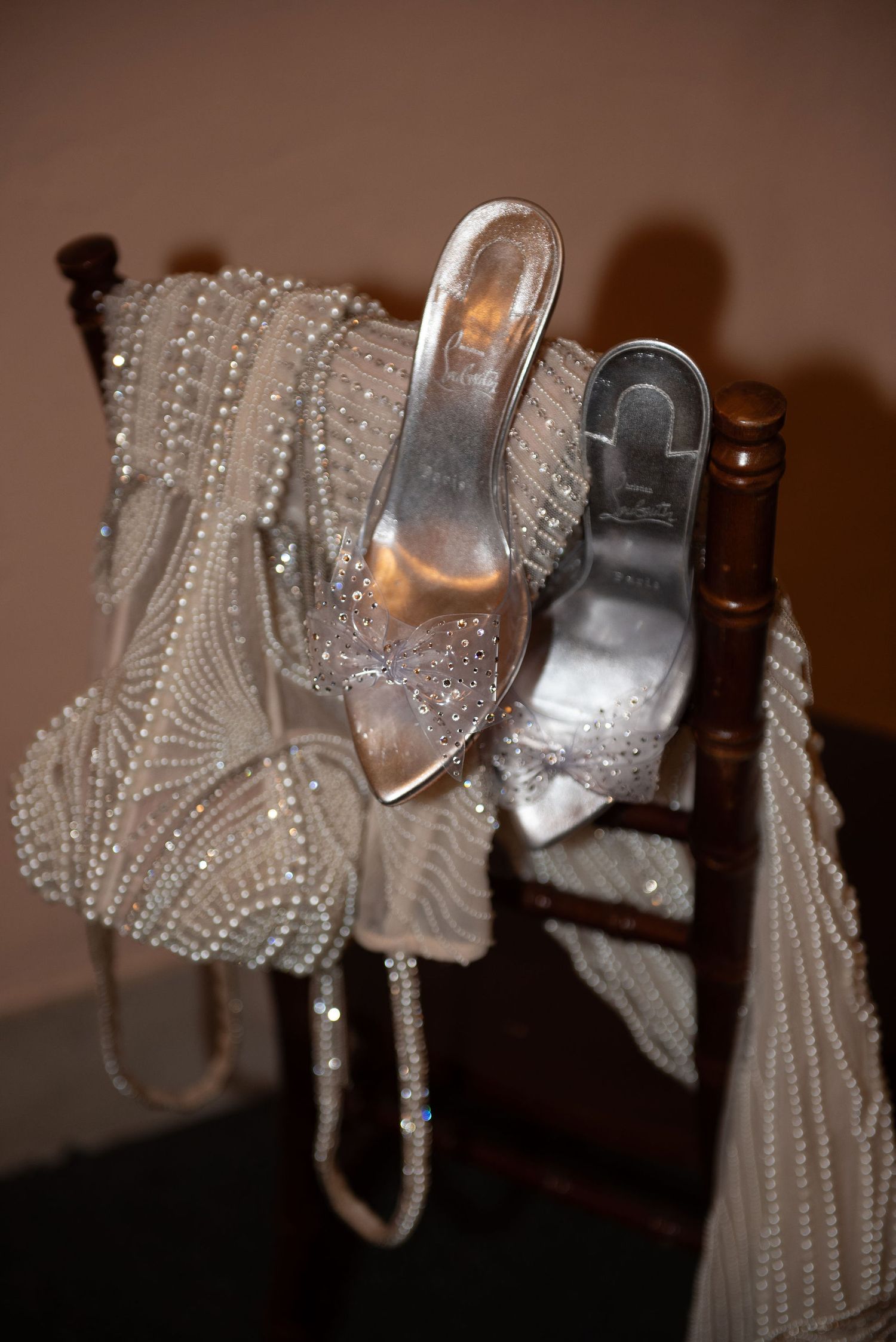 Row of sparkly beaded wedding shoes and accessories displayed against brown background.