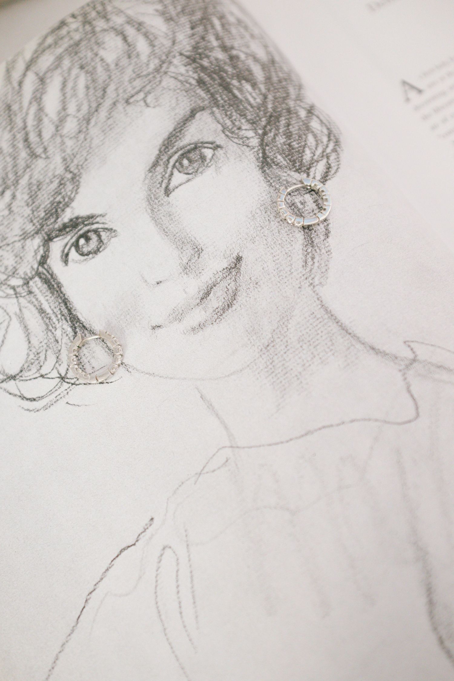 Pencil sketch portrait showing curly hair and a gentle smile in a soft artistic style.