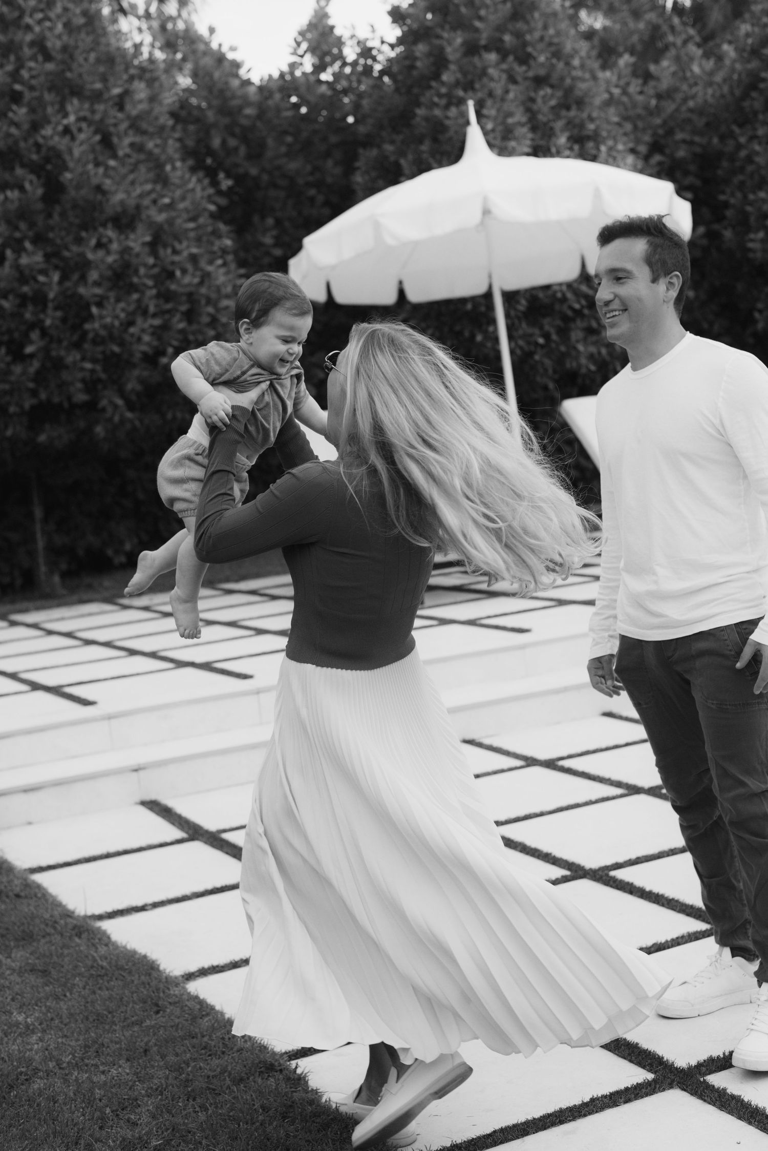 A black and white photo of a family playing on modern garden steps with a white umbrella.