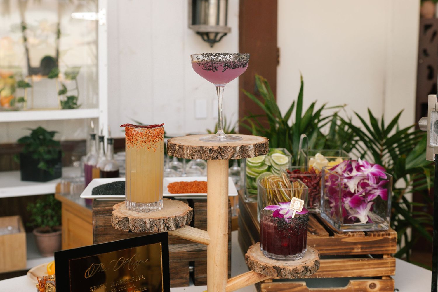 Rustic wood slices serve as decorative coasters and centerpieces on a restaurant table with drinks and floral accents.
