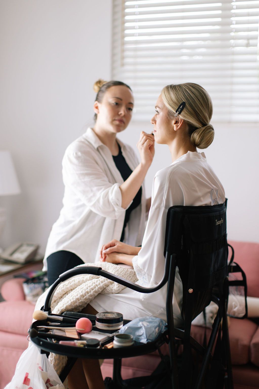Getting ready scene with makeup application in bright room.