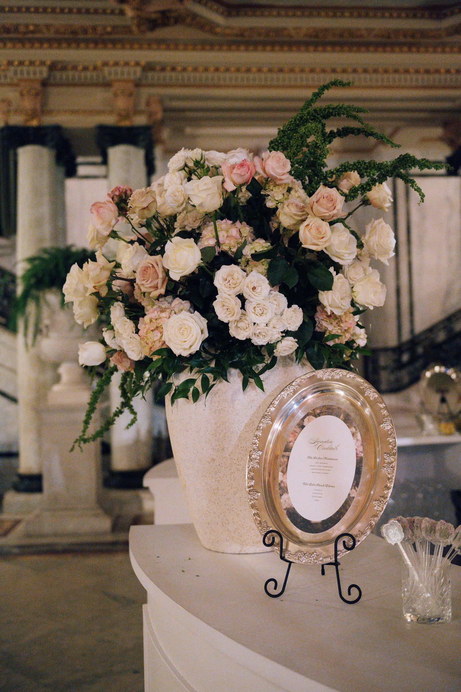 Romantic floral centerpieces with blush roses and decorative frames on display at a wedding reception.