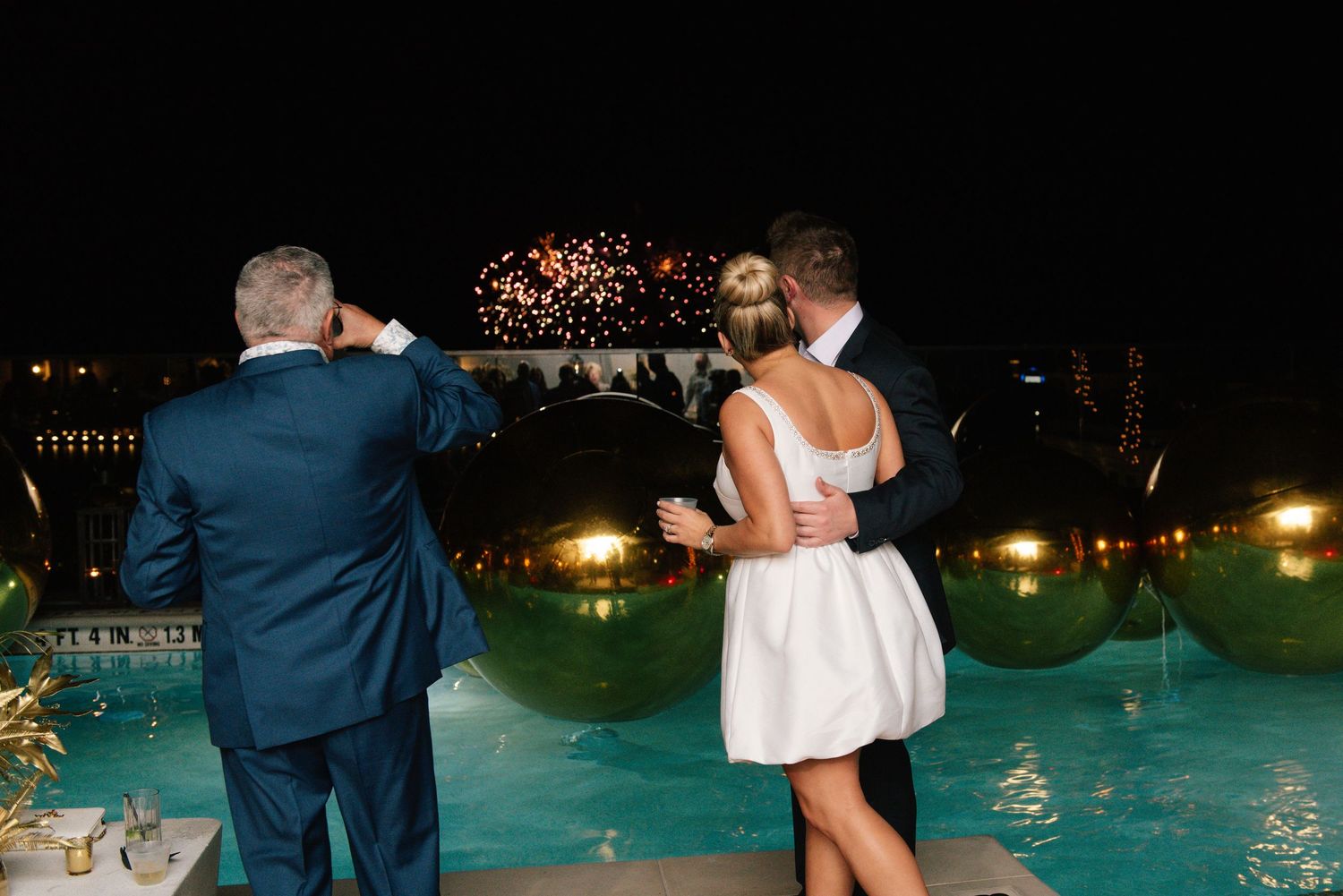 Evening celebration by an illuminated pool with guests enjoying the nighttime atmosphere.