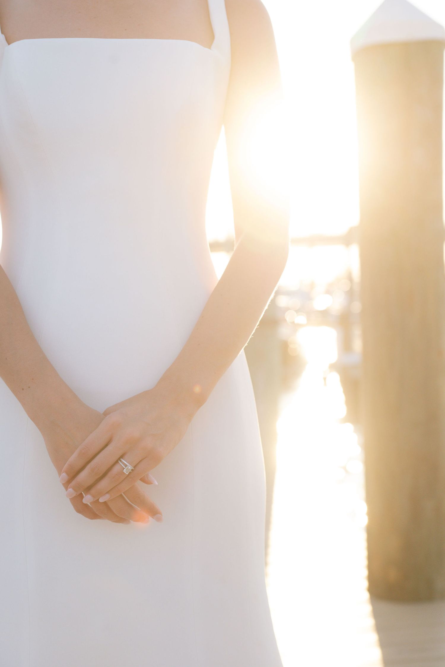 Close-up details of a bride in a white wedding dress with sunlight creating a warm glow.