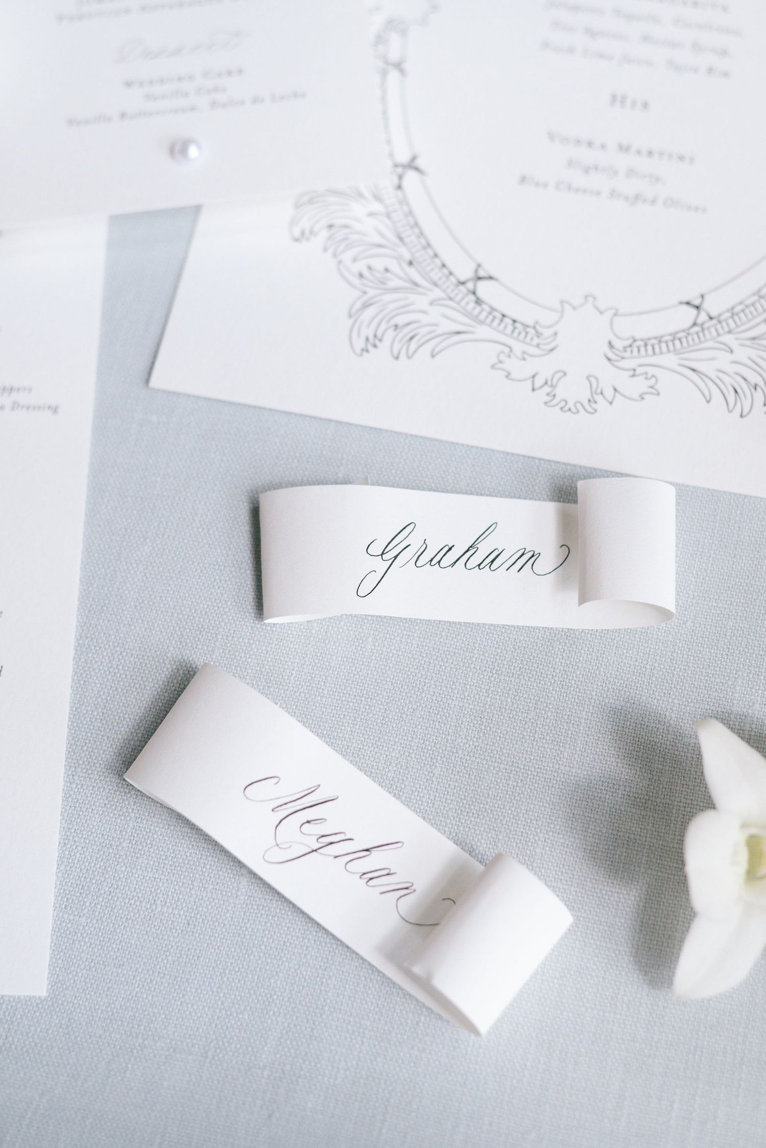 Wedding name cards with elegant calligraphy displayed on light gray background with floral details.