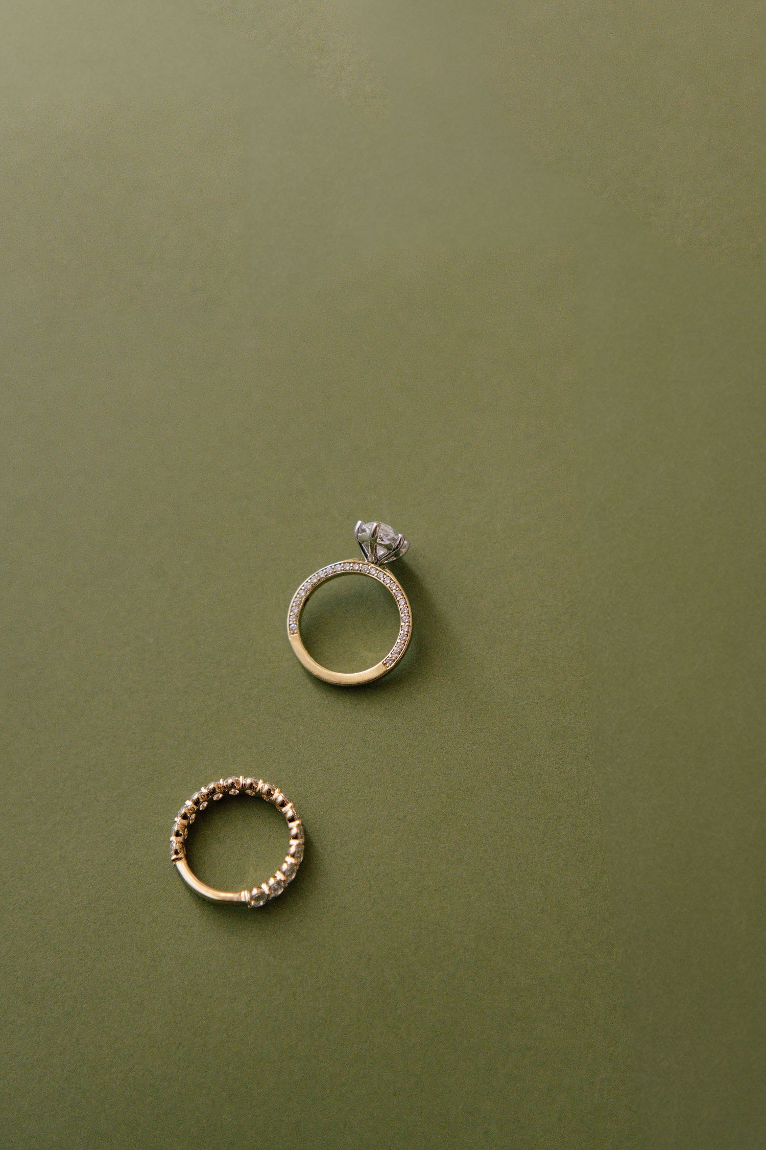 Two elegant wedding rings displayed on olive green background.