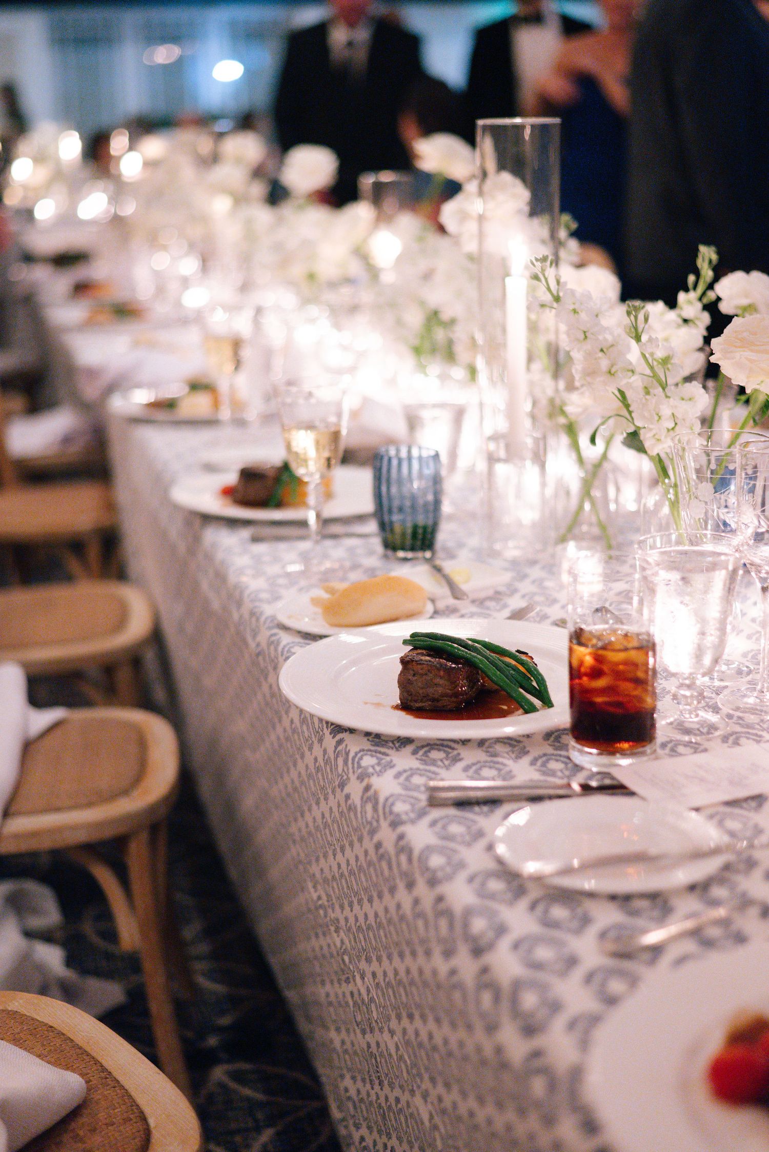 Elegant table settings with white linens, glassware and place settings at a formal dinner event.
