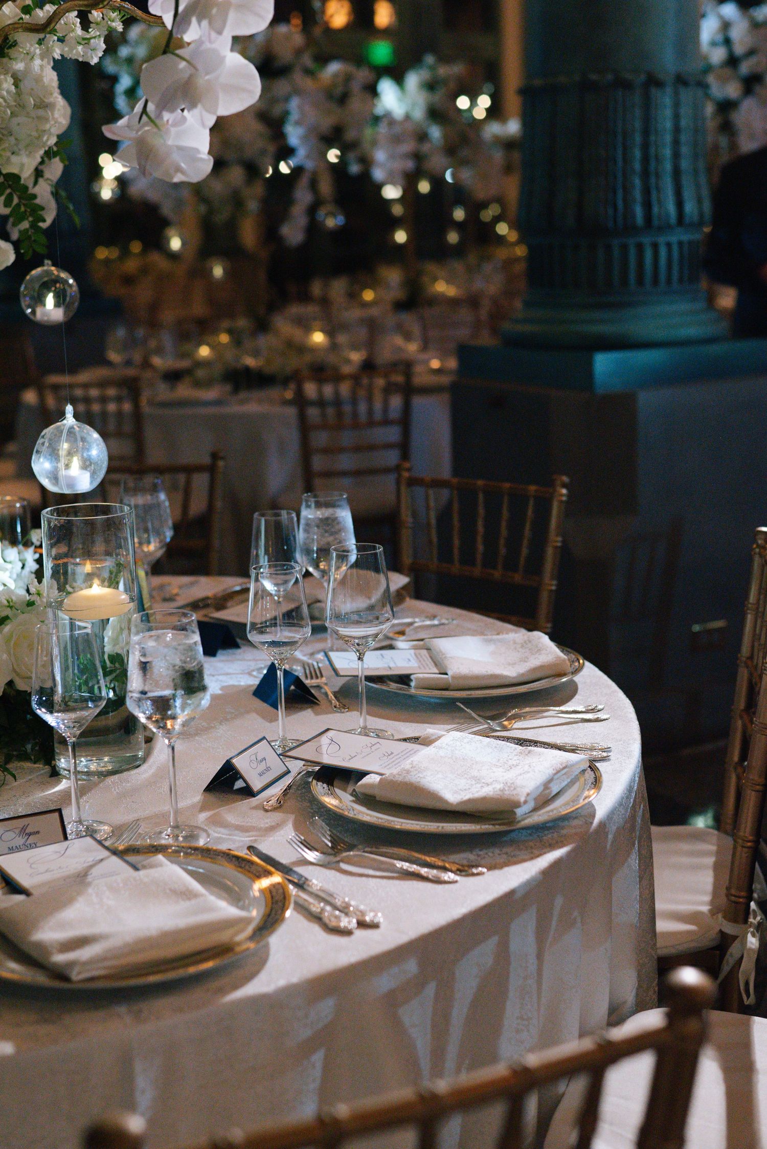Elegant wedding reception table set with white linens, crystal glasses, and floral centerpieces.