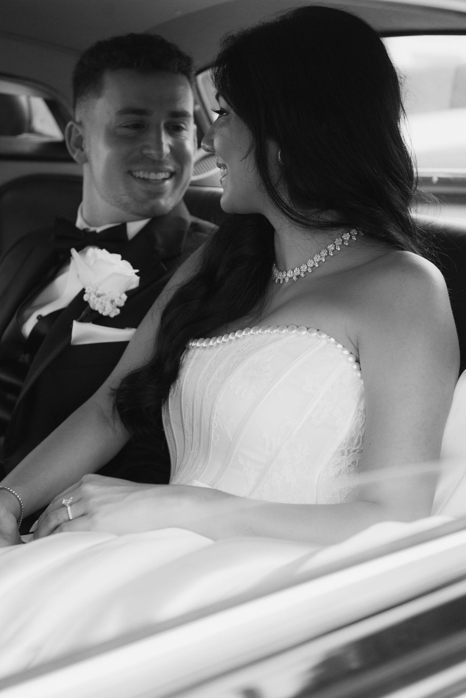 Newlyweds share intimate moments in the back of their wedding car.