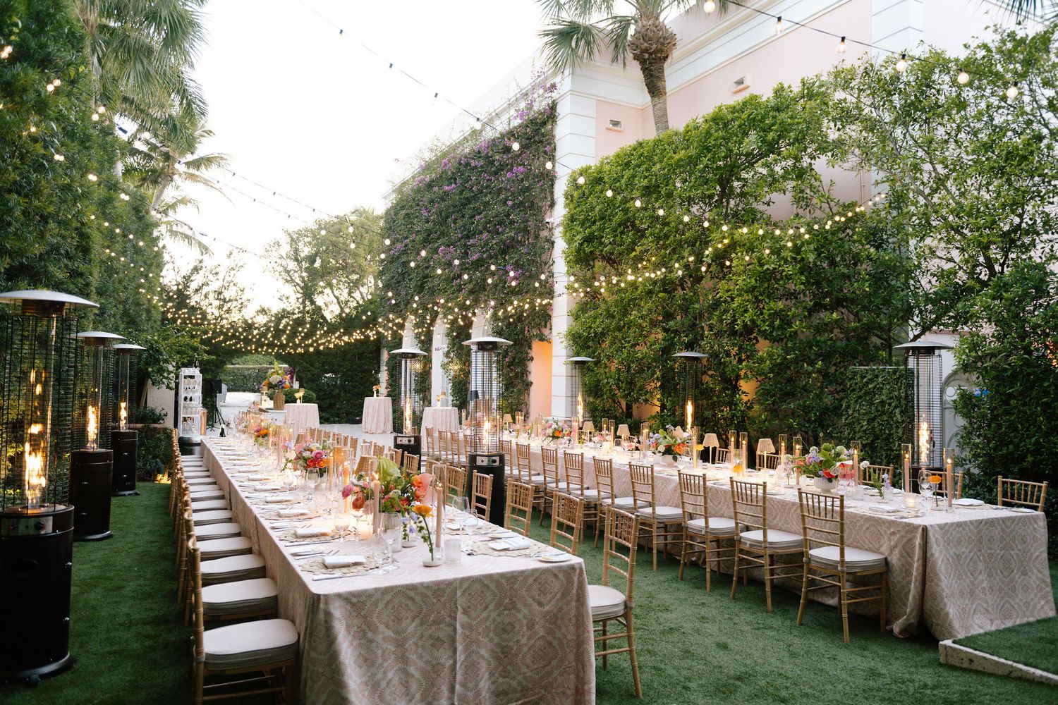 Elegant outdoor wedding reception setup with long tables under string lights.