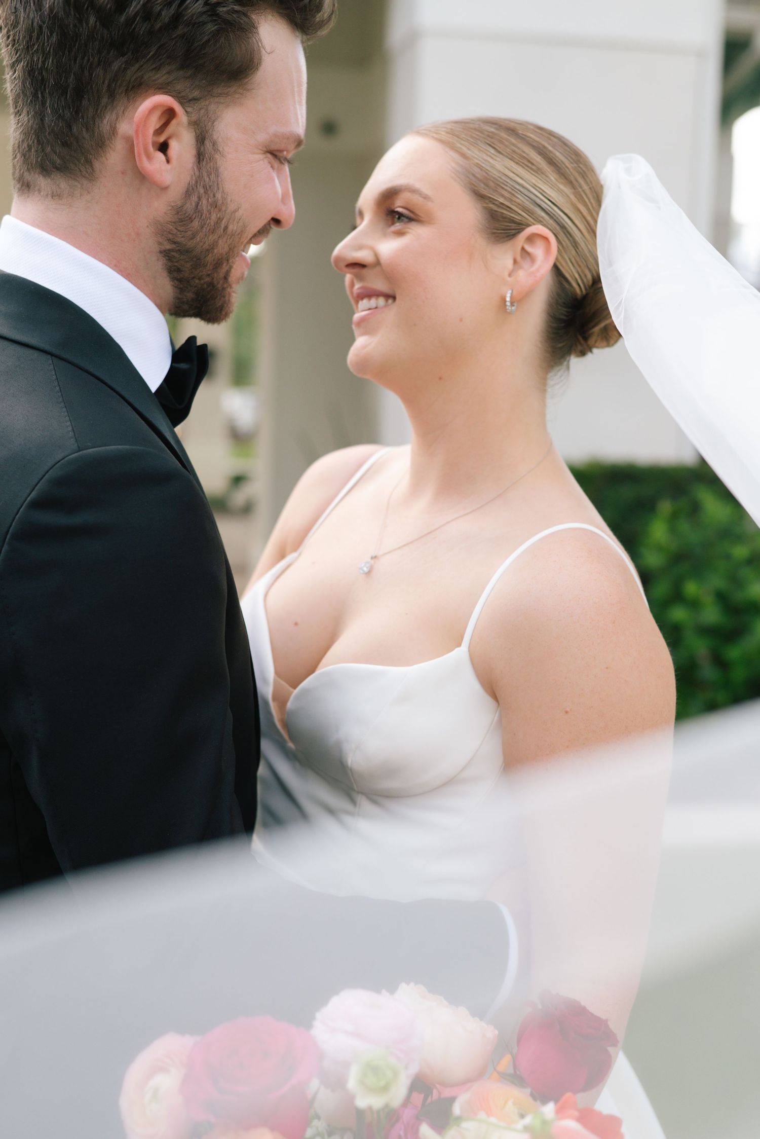 A romantic wedding moment captured between newlyweds as they share a joyful smile through a flowing veil.