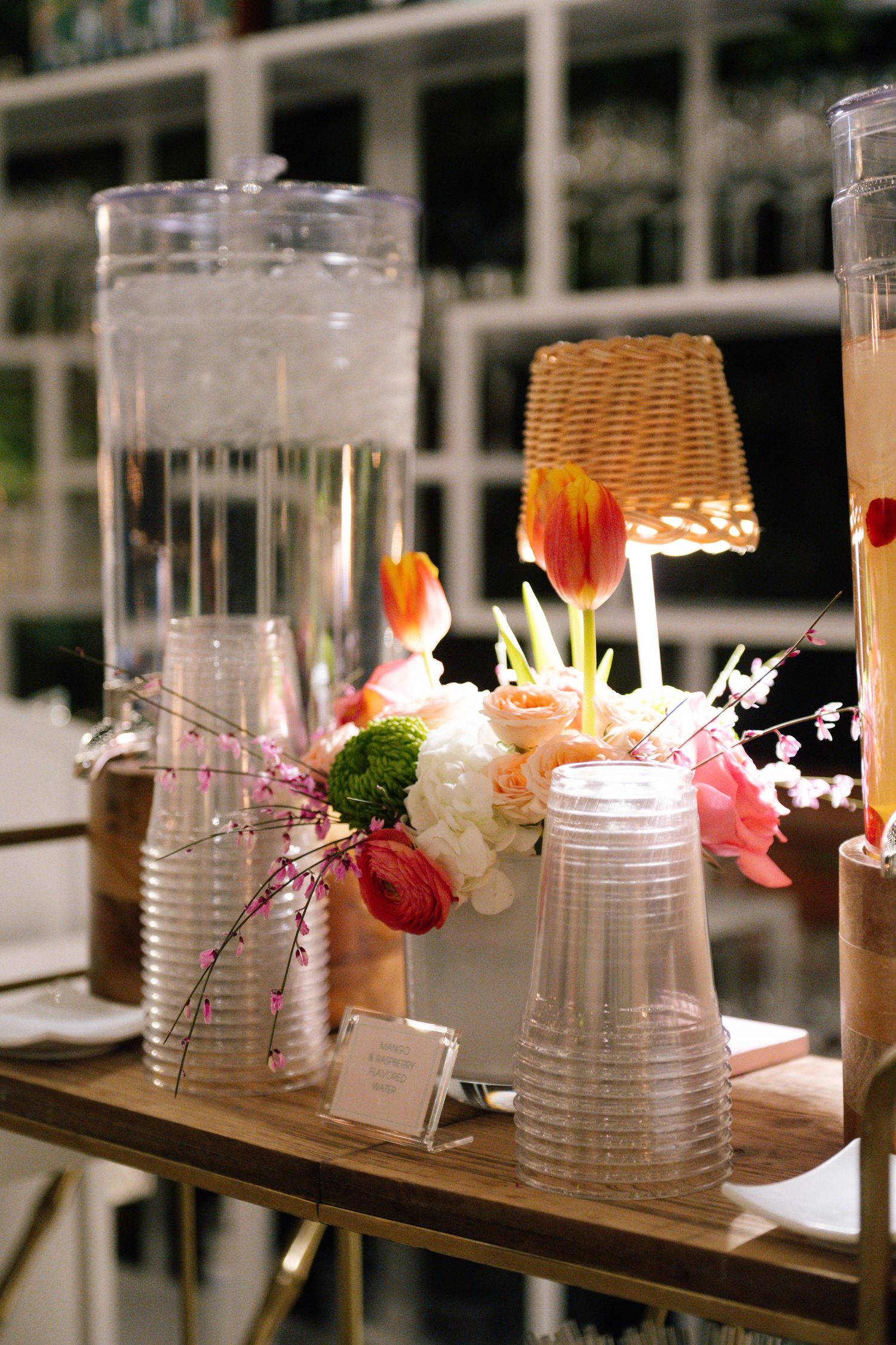 Decorative glass vases and floral arrangements line a wooden table at a wedding reception.